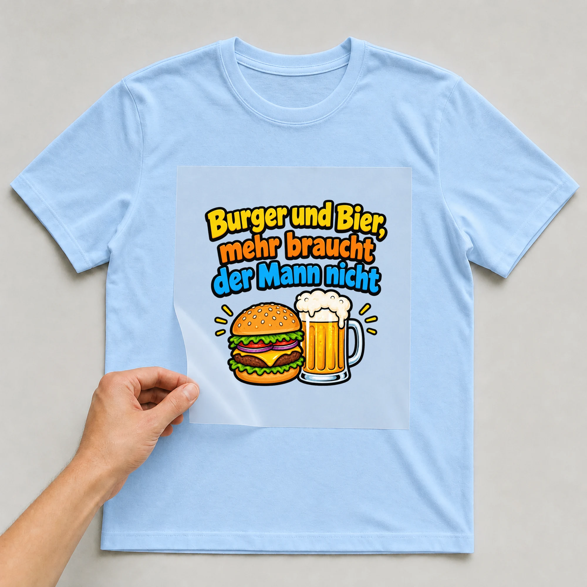 Bügelbild „Burger und Bier, mehr braucht der Mann nicht“ auf babyblauem T-Shirt, Folie wird aufgelegt
