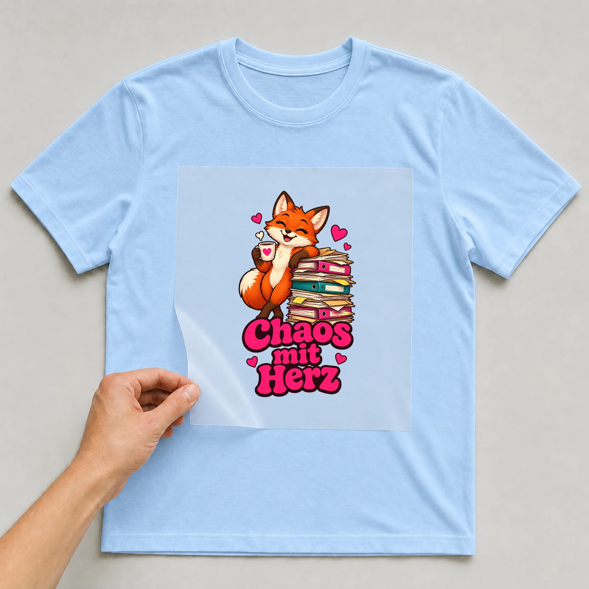 Bügelbild „Chaos mit Herz“ auf babyblauem T-Shirt, Folie wird aufgelegt