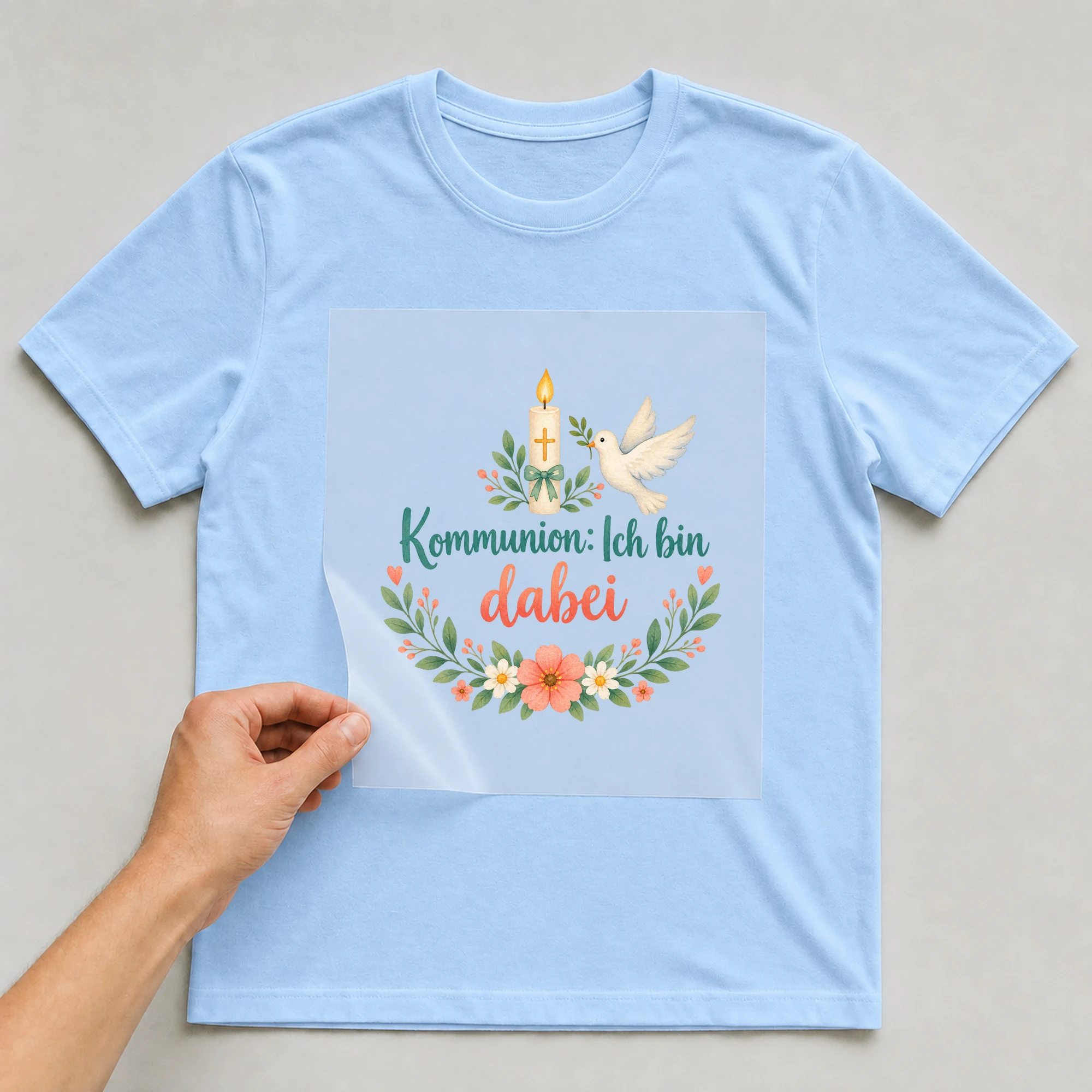 Bügelbild „Kommunion: Ich bin dabei“ auf babyblauem T-Shirt, Folie wird aufgelegt