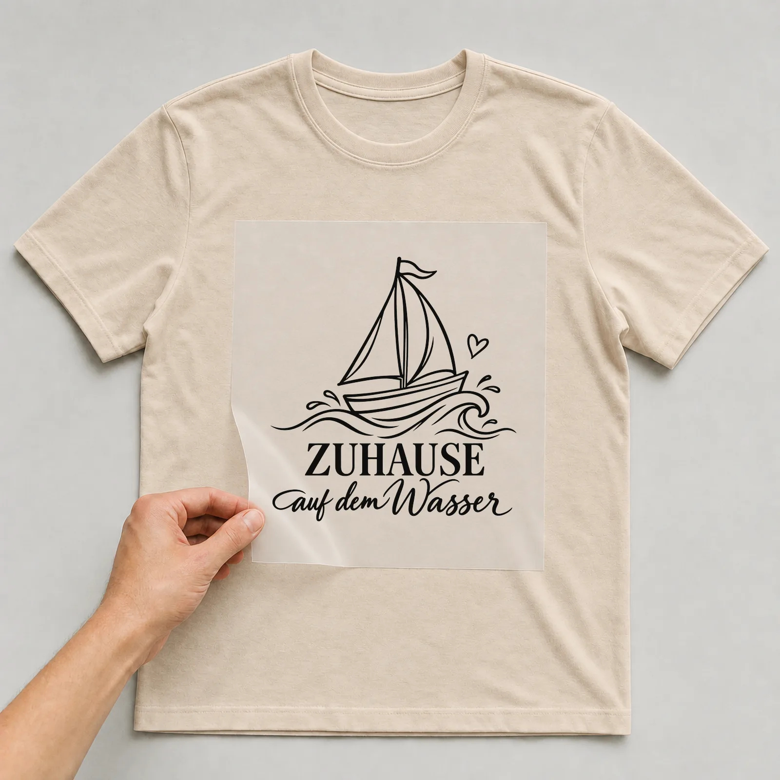 Bügelbild „Zuhause auf dem Wasser“ auf beigem T-Shirt, Folie wird aufgelegt
