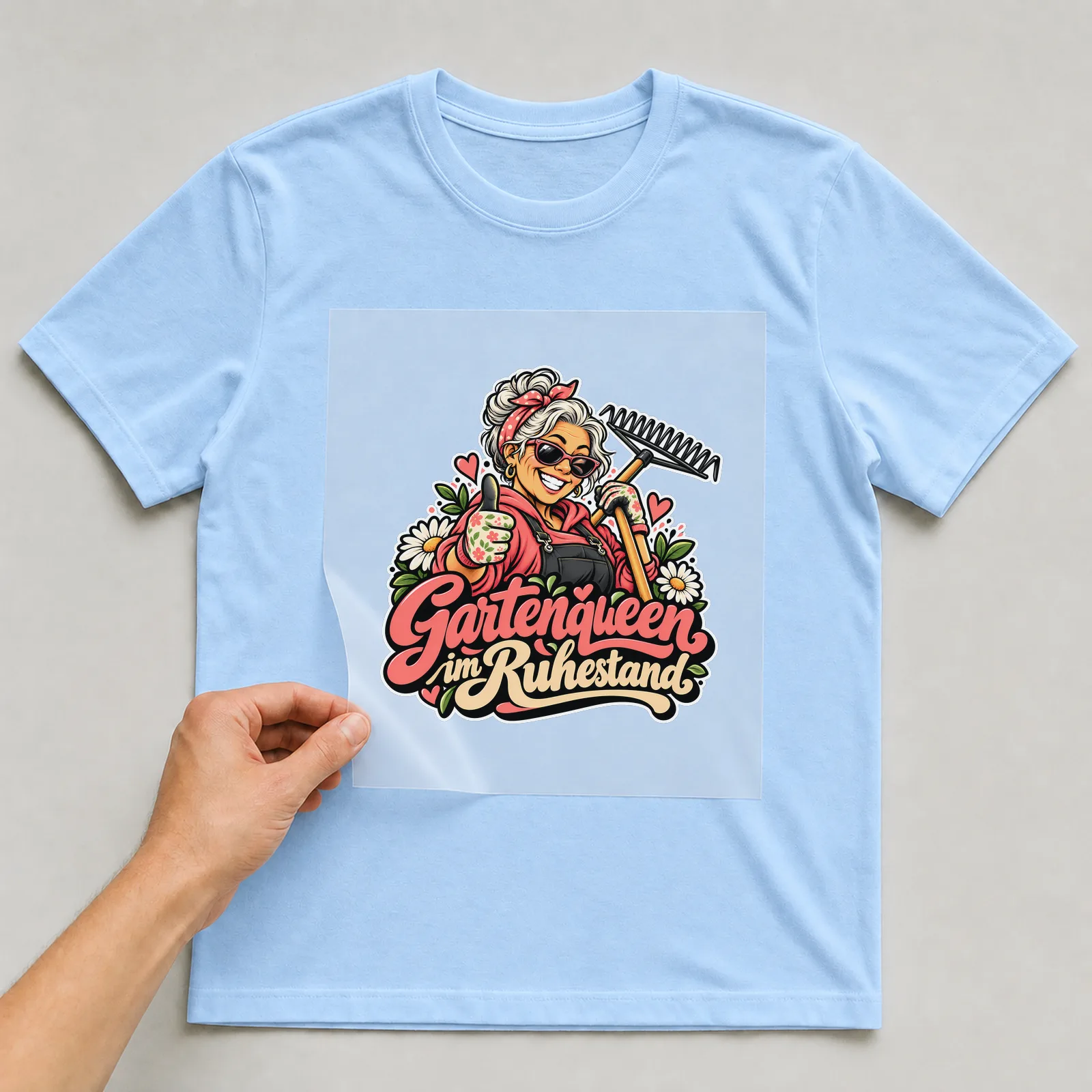 Bügelbild „Gartenqueen im Ruhestand“ auf hellblauem T-Shirt, Folie wird aufgelegt