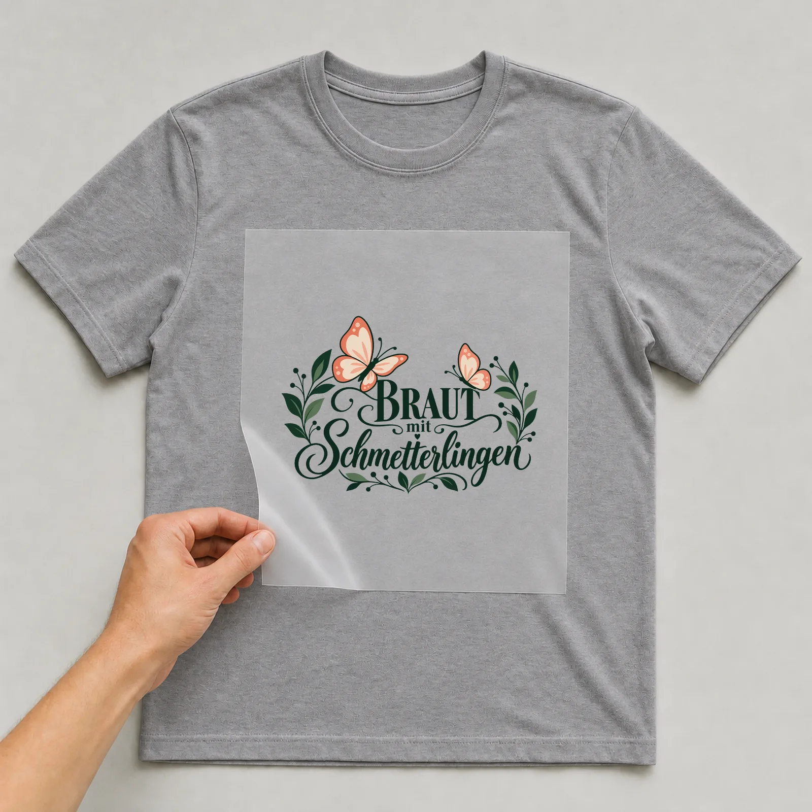 Bügelbild „Braut mit Schmetterlingen“ auf grauem T-Shirt, Folie wird aufgelegt