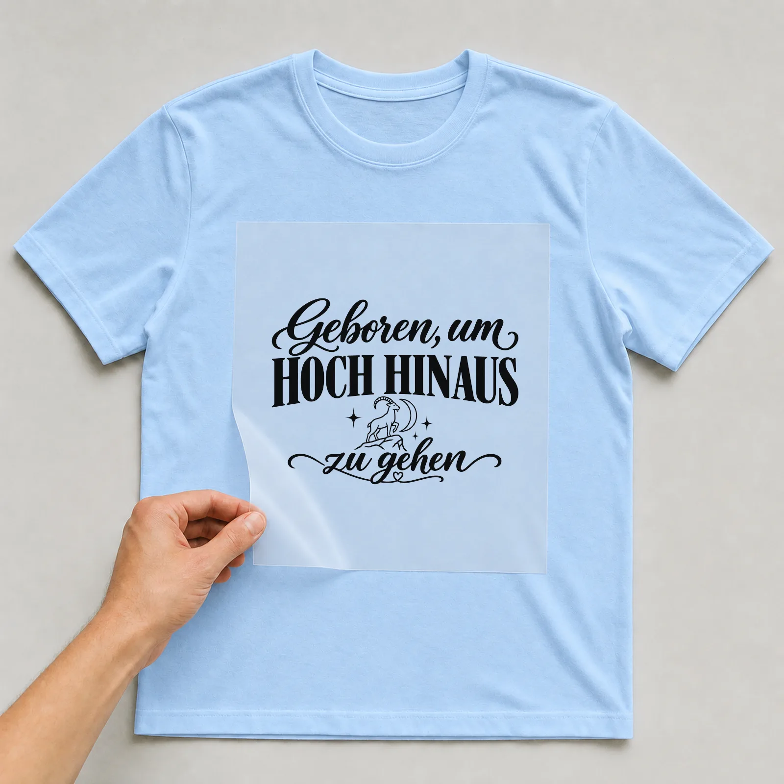 Bügelbild „Geboren, um hoch hinaus zu gehen“ auf hellblauem T-Shirt, Folie wird aufgelegt