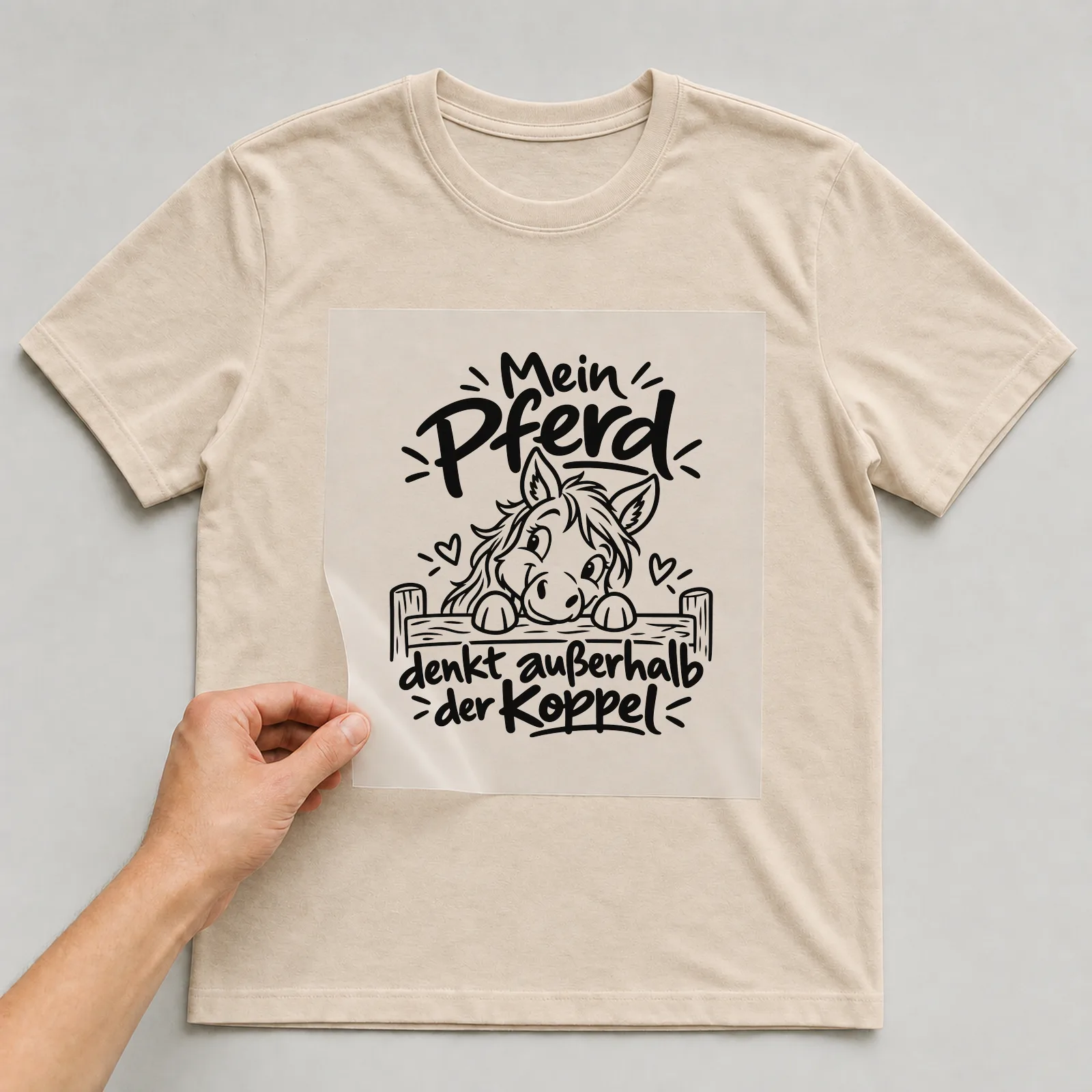 Bügelbild „Mein Pferd denkt außerhalb der Koppel“ auf beigem T-Shirt, Folie wird aufgelegt