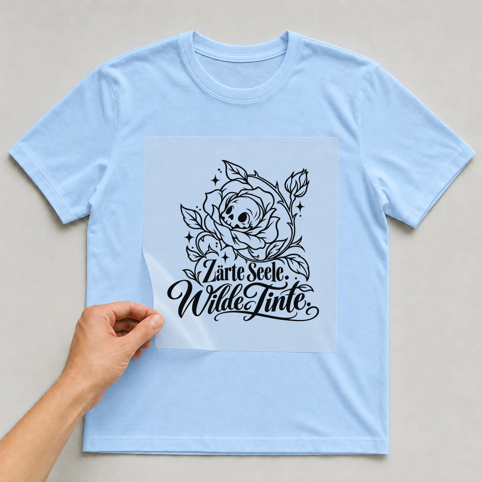 Bügelbild „Zarte Seele. Wilde Tinte.“ auf hellblauem T-Shirt, Folie wird aufgelegt