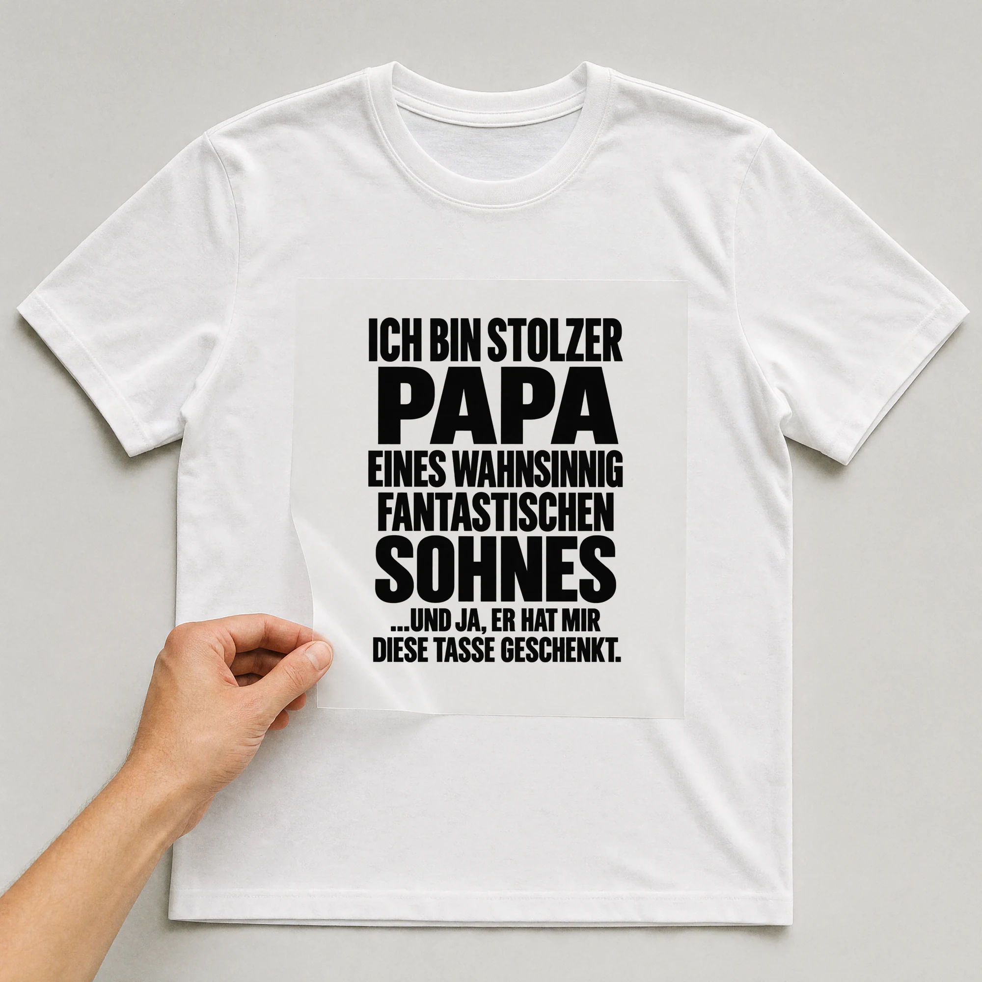 Bügelbild „Ich bin stolzer Papa eines wahnsinnig fantastischen Sohnes ...Und ja, er hat“ auf weißem T-Shirt, Folie wird aufgelegt