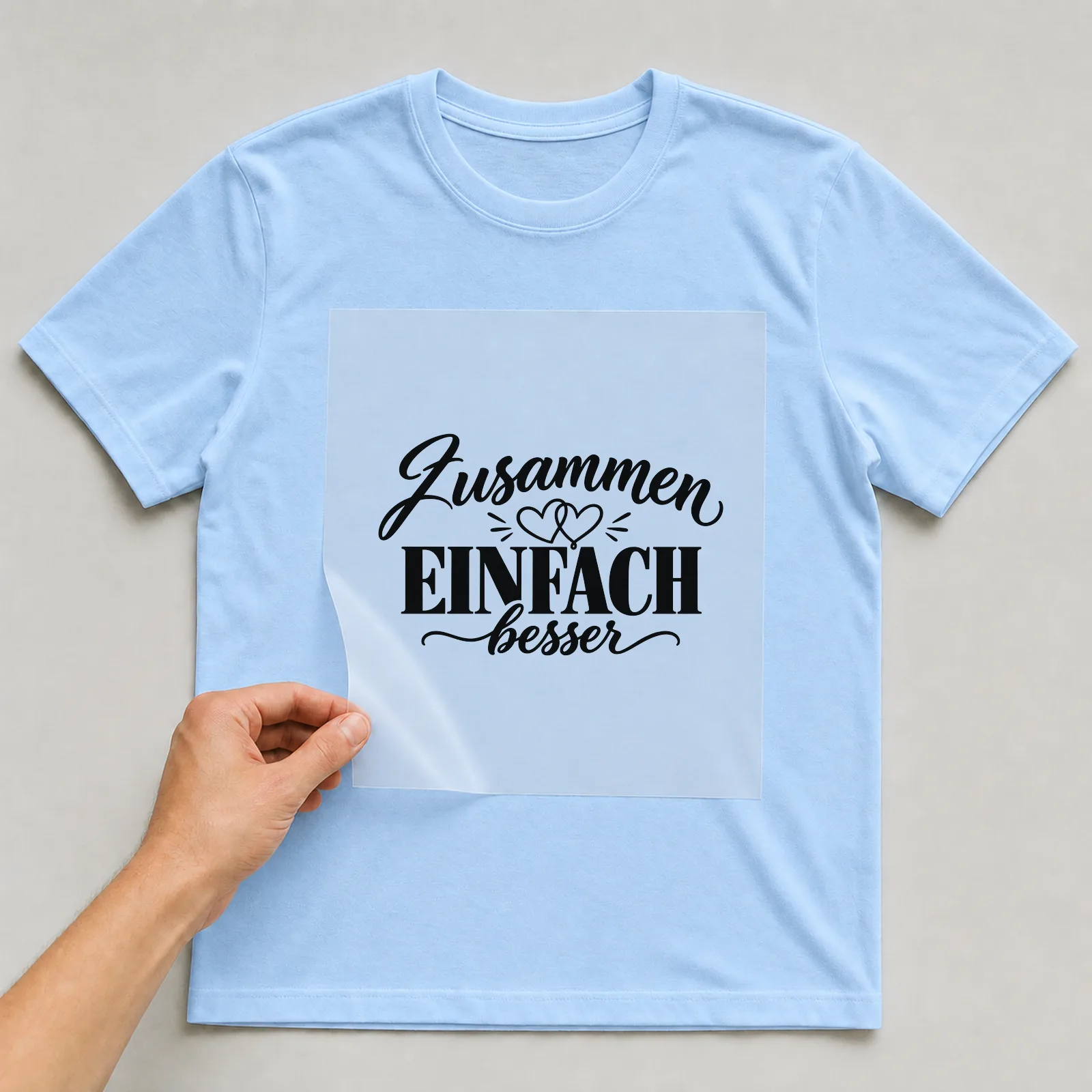 Bügelbild „Zusammen einfach besser“ auf hellblauem T-Shirt, Folie wird aufgelegt