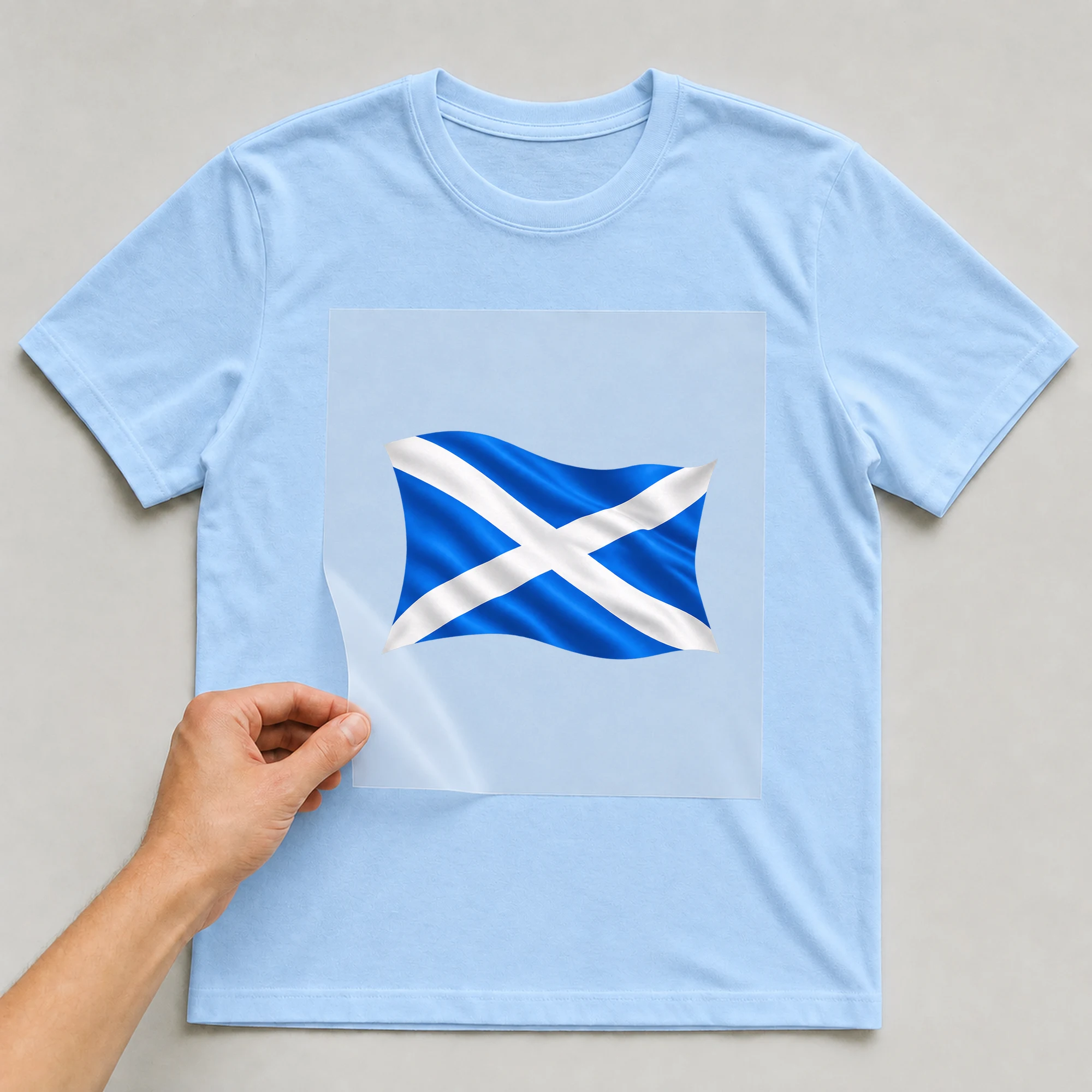 Bügelbild „Länder Flagge Schottland“ auf babyblauem T-Shirt, Folie wird aufgelegt