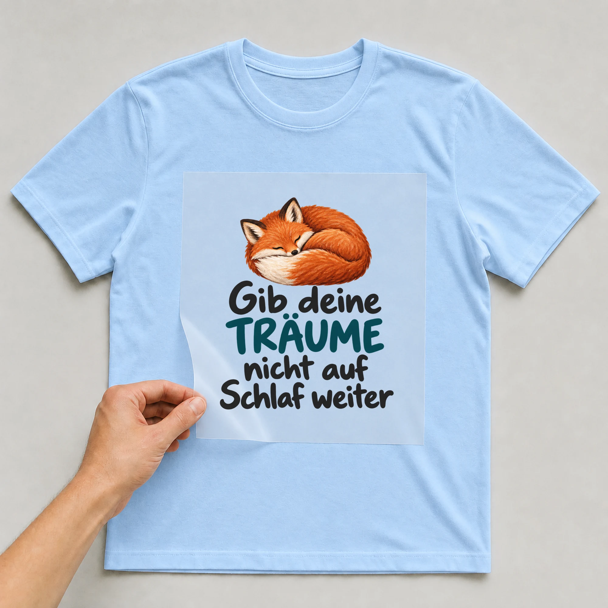 Bügelbild „Gib deine TRÄUME nicht auf Schlaf weiter“ auf babyblauem T-Shirt, Folie wird aufgelegt