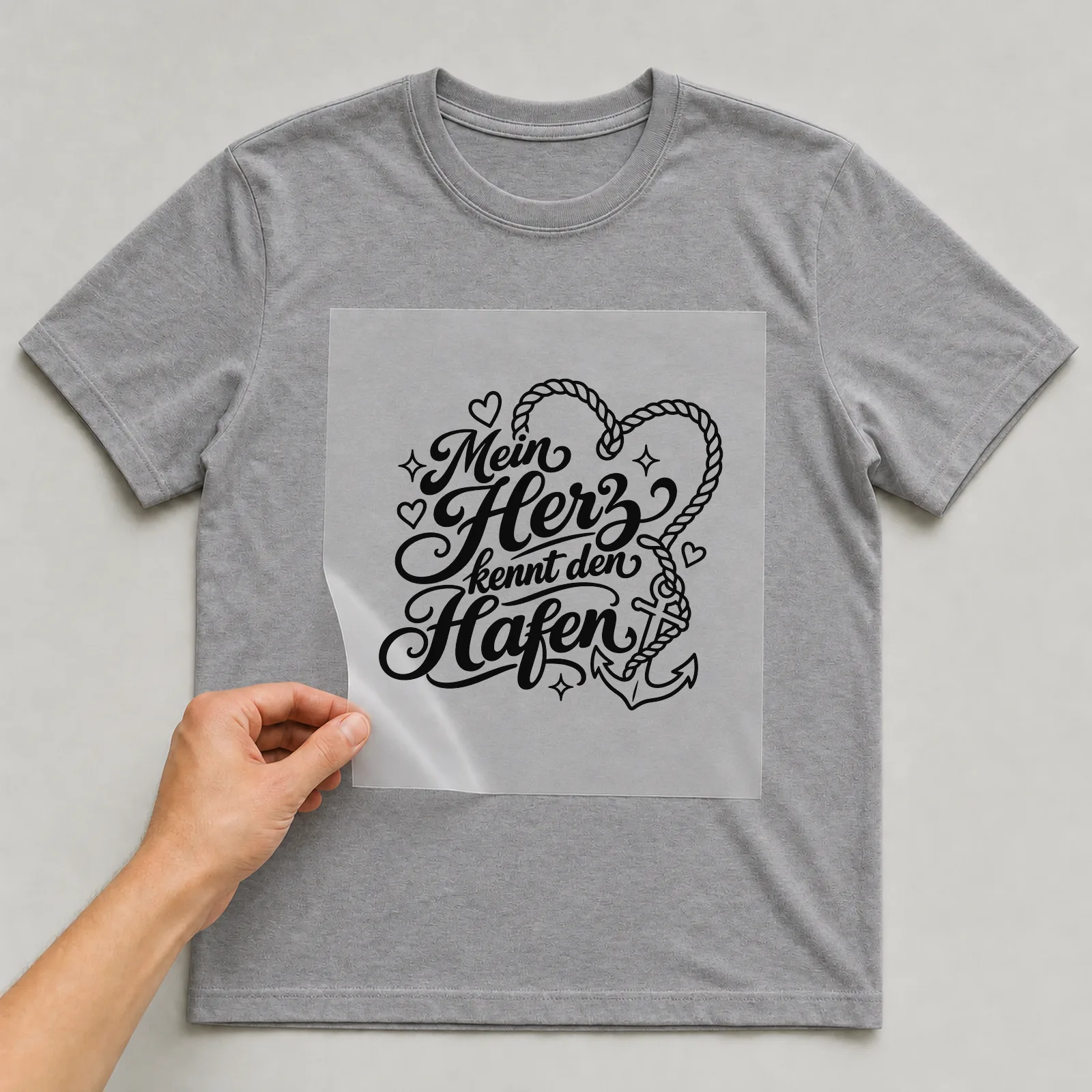 Bügelbild „Mein Herz kennt den Hafen“ auf grauem T-Shirt, Folie wird aufgelegt