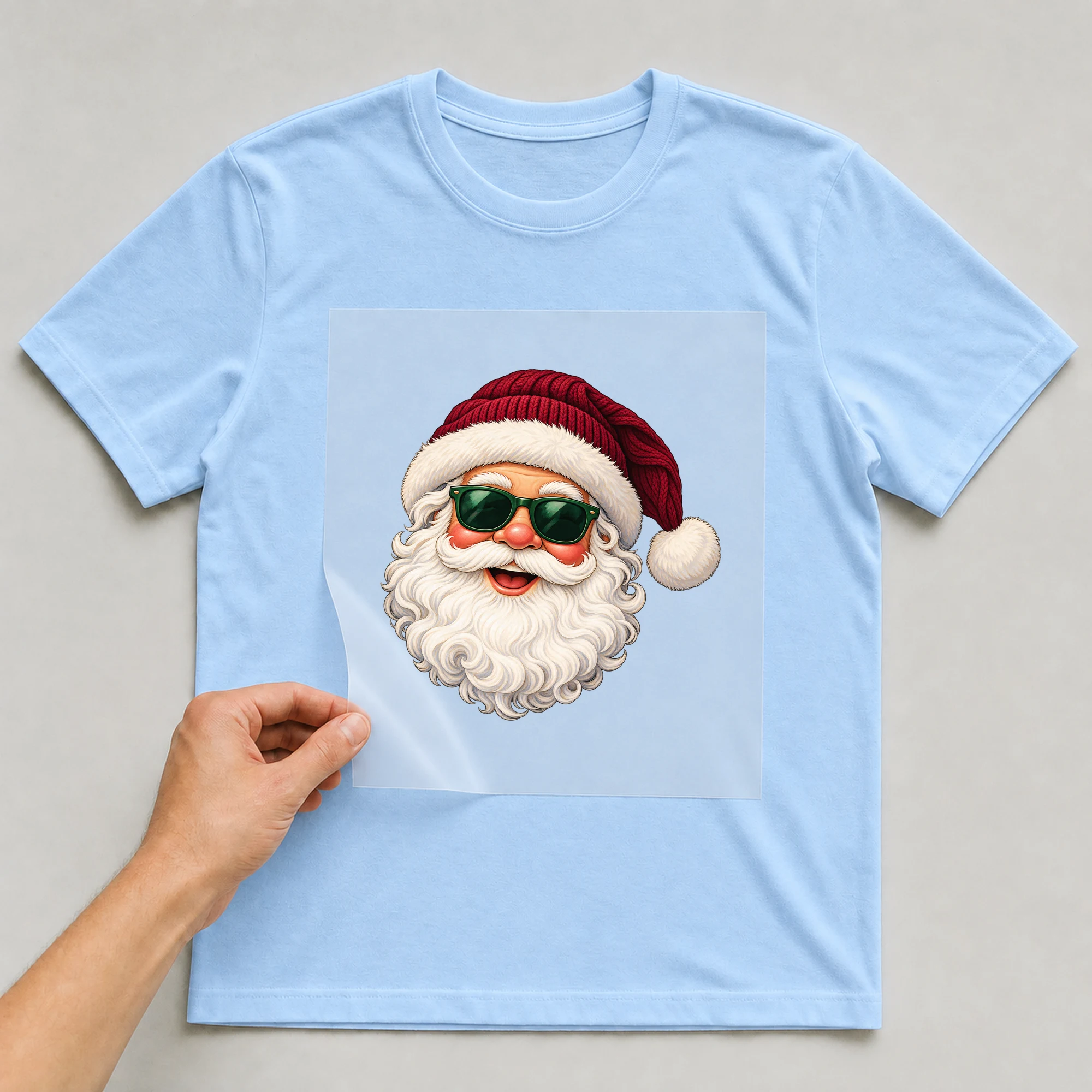 Bügelbild „Cooler Weihnachtsmann“ auf babyblauem T-Shirt, Folie wird aufgelegt