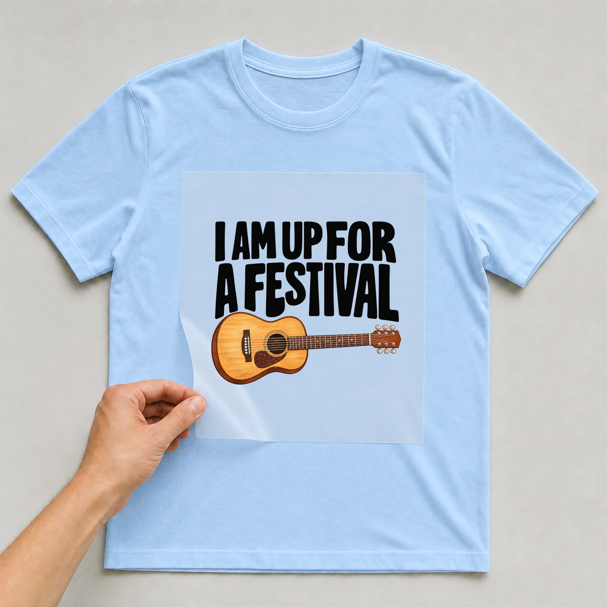 Bügelbild „I Am Up For A Festival“ auf babyblauem T-Shirt, Folie wird aufgelegt