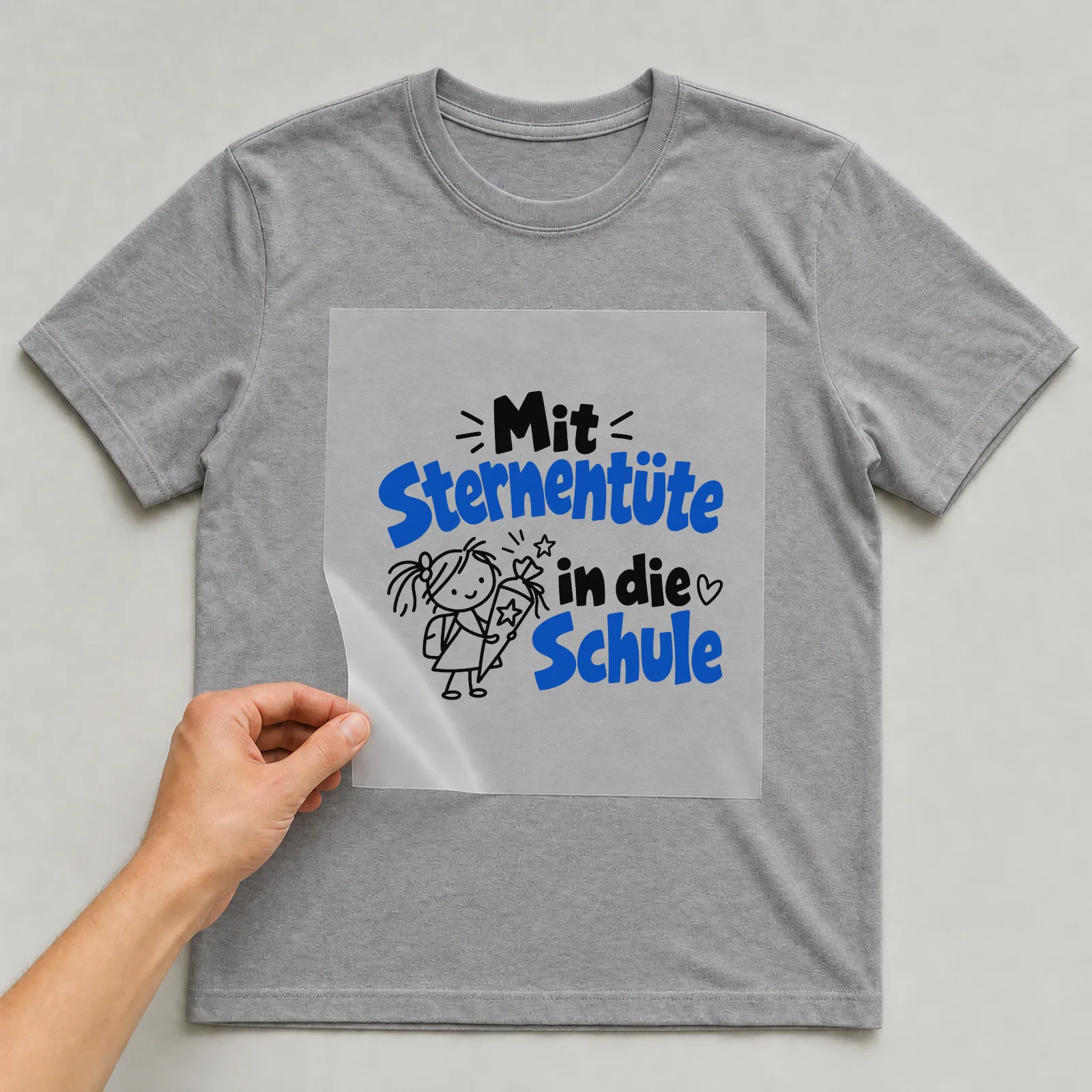 Bügelbild „Mit Sternentüte in die Schule“ auf grauem T-Shirt, Folie wird aufgelegt