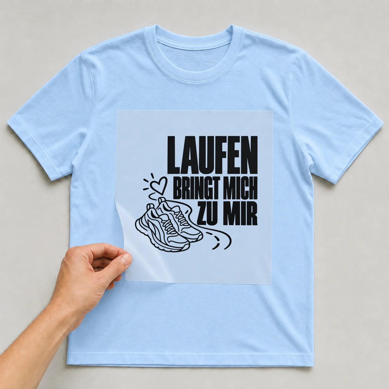 Bügelbild „Laufen bringt mich zu mir“ auf hellblauem T-Shirt, Folie wird aufgelegt