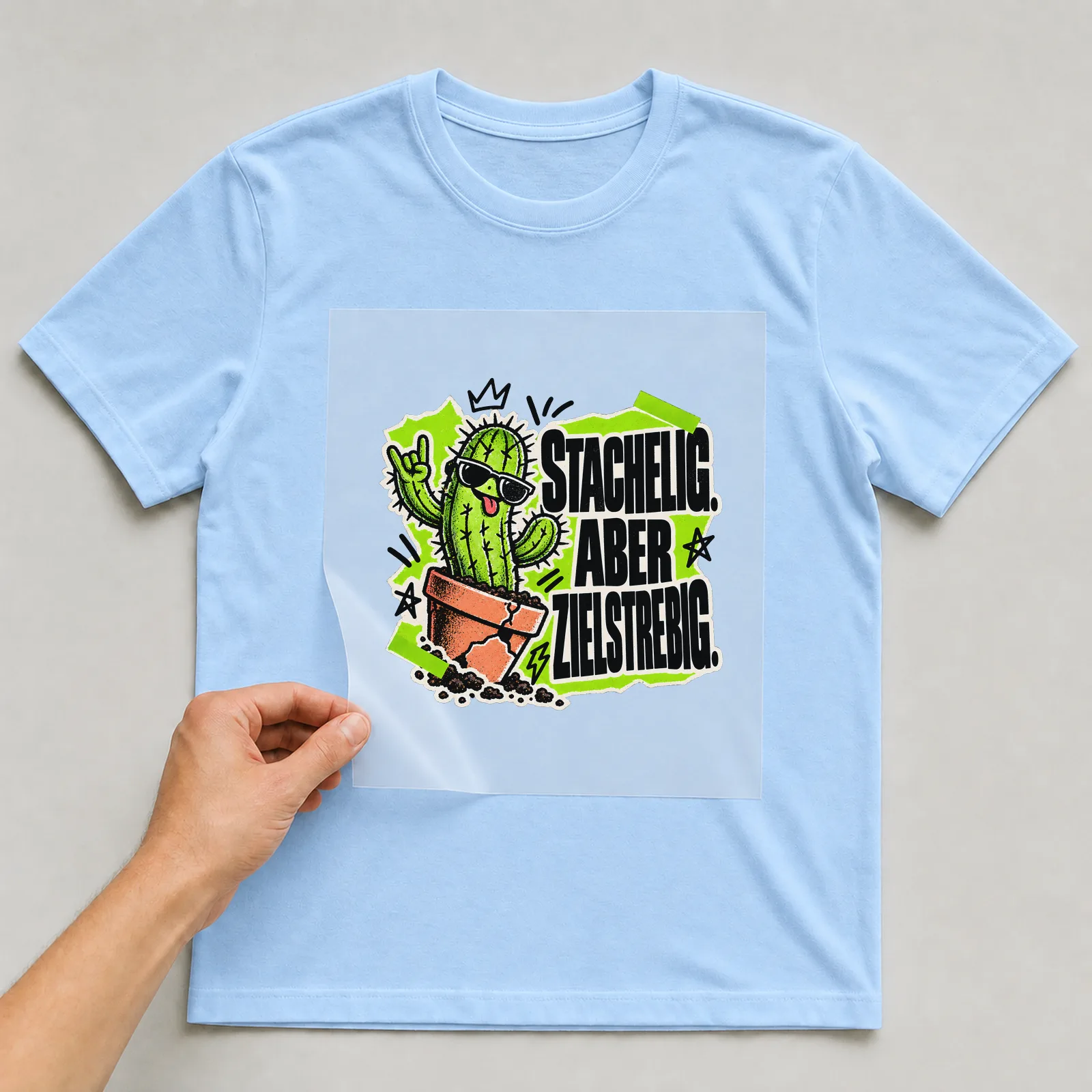 Bügelbild „Stachelig. Aber zielstrebig.“ auf hellblauem T-Shirt, Folie wird aufgelegt