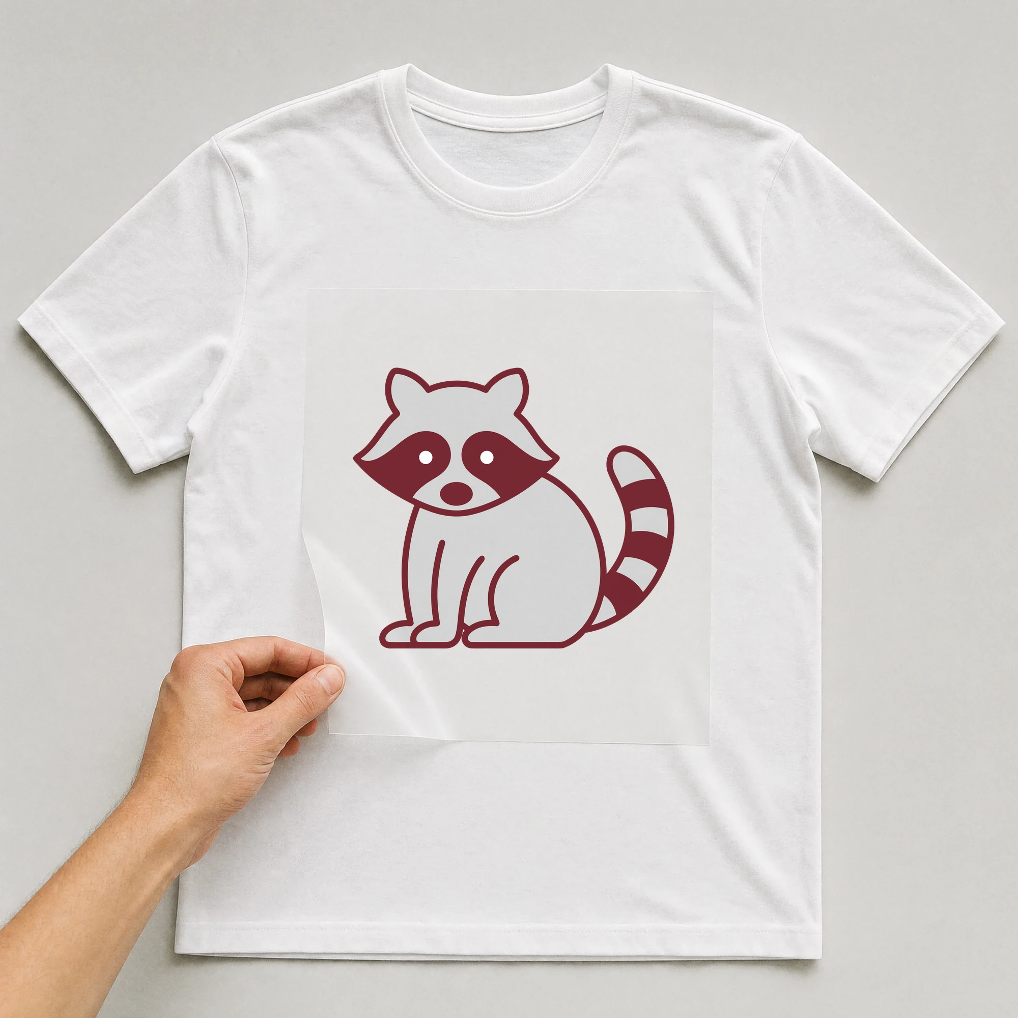 Bügelbild „Waschbär“ auf weißem T-Shirt, Folie wird aufgelegt