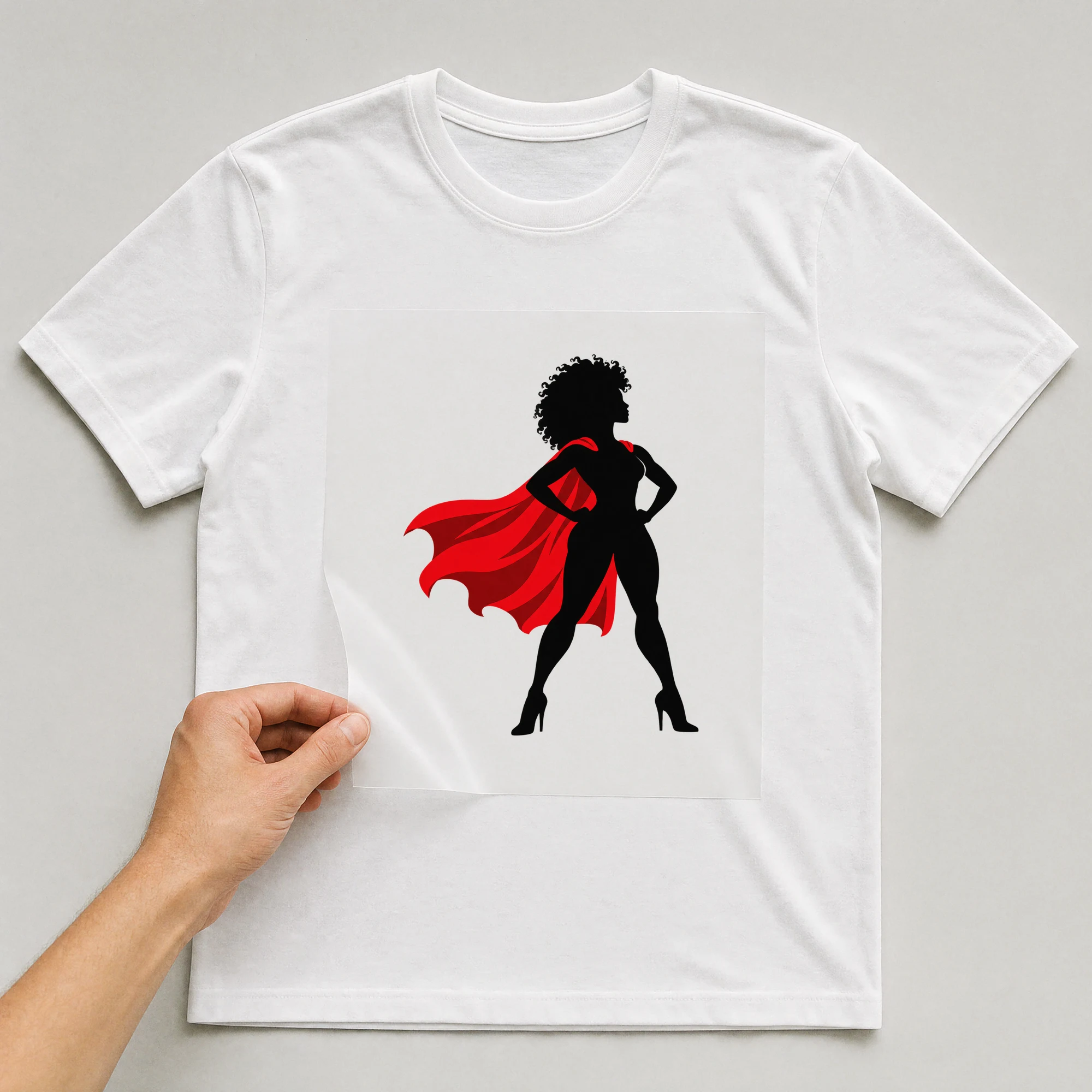 Bügelbild „Superheldin mit Cape“ auf weißem T-Shirt, Folie wird aufgelegt