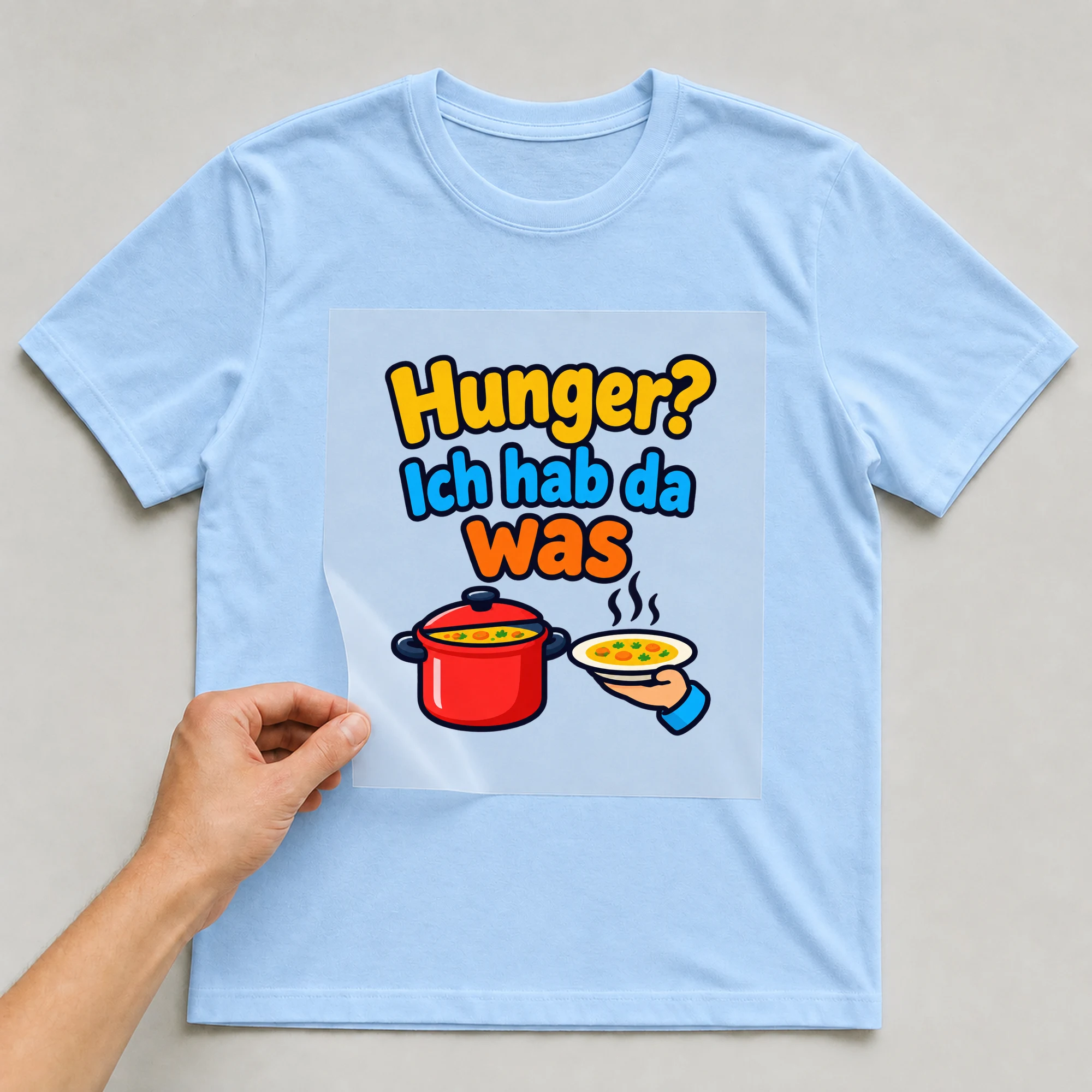 Bügelbild „Hunger? Ich hab da was“ auf babyblauem T-Shirt, Folie wird aufgelegt