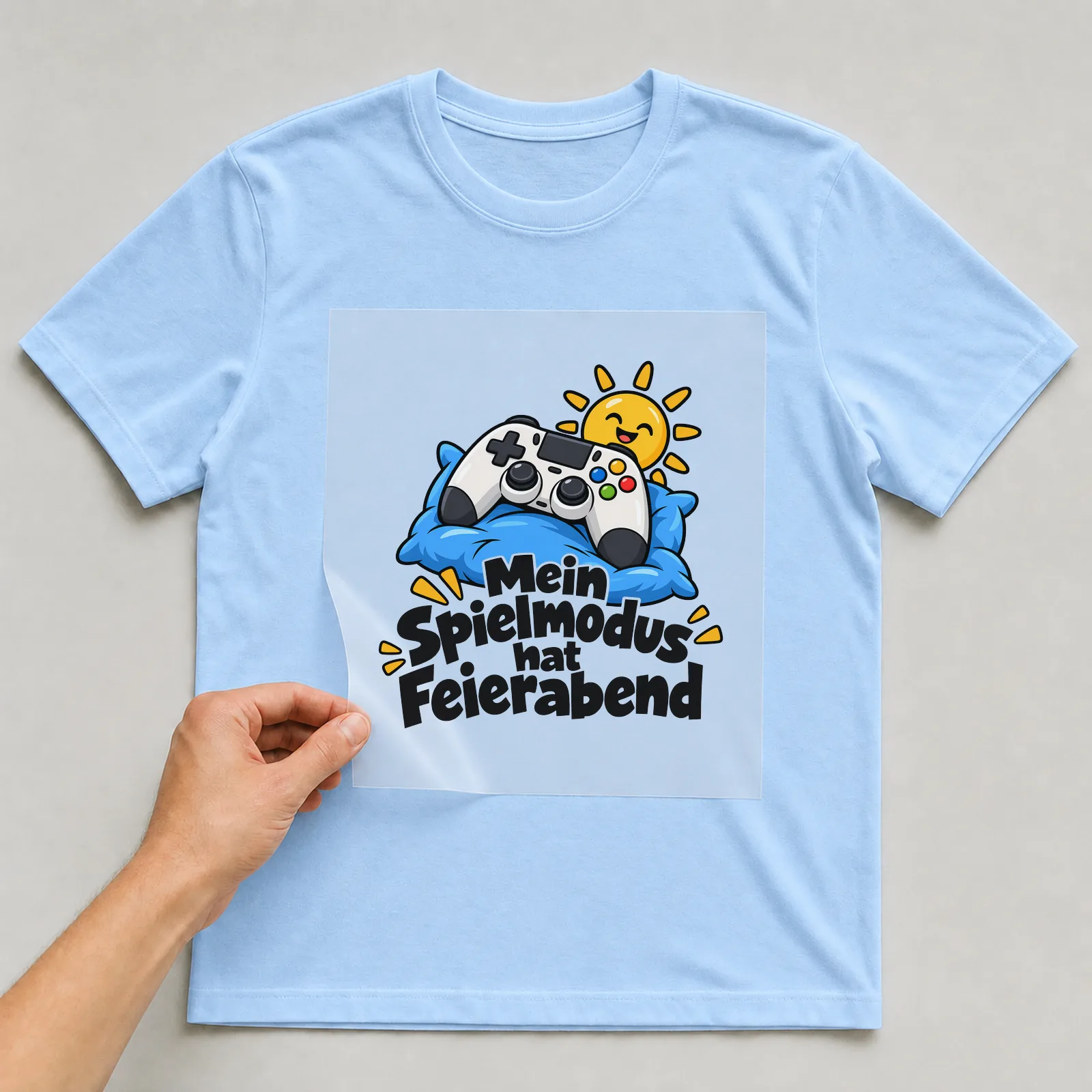 Bügelbild „Mein Spielmodus hat Feierabend“ auf hellblauem T-Shirt, Folie wird aufgelegt