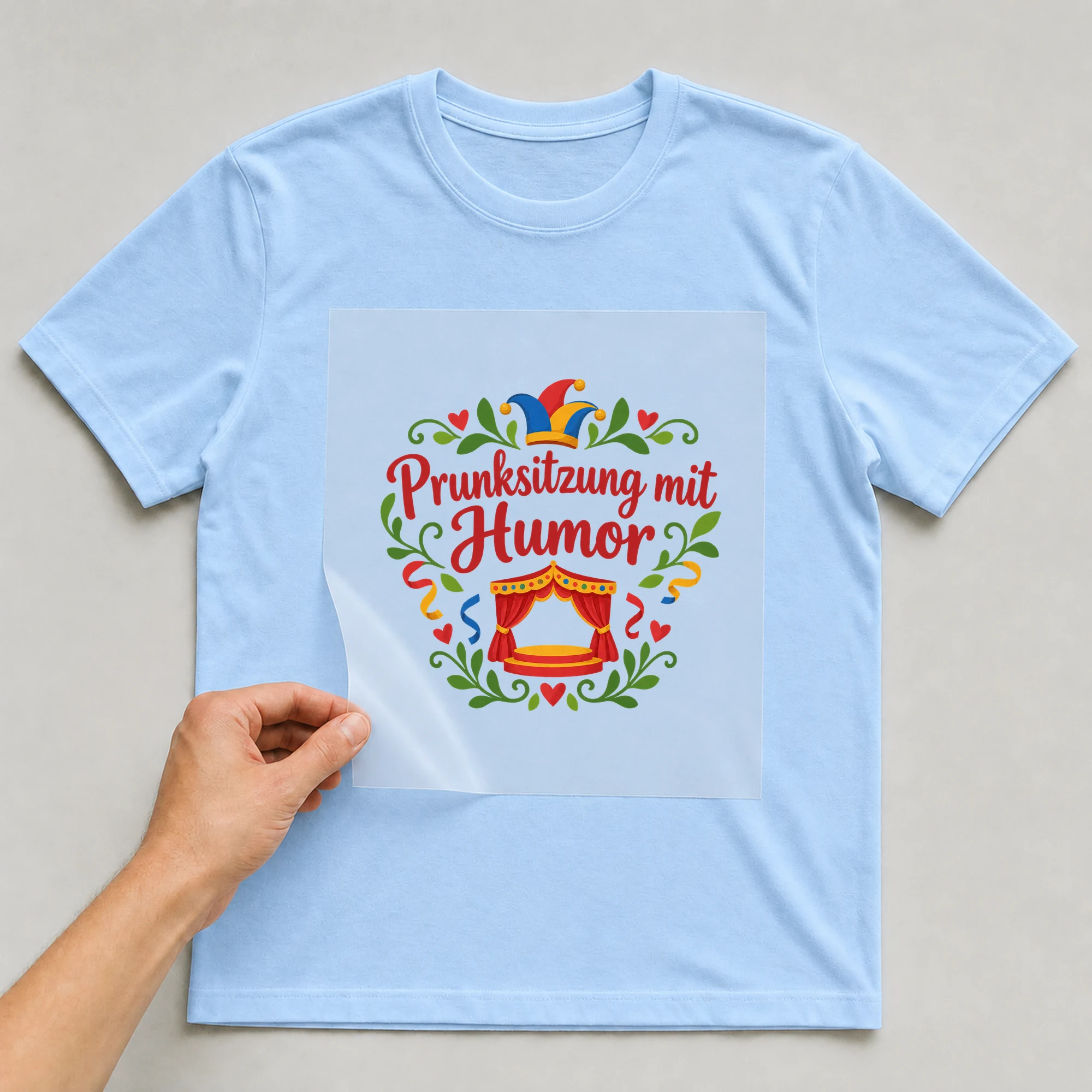 Bügelbild „Prunksitzung mit Humor“ auf babyblauem T-Shirt, Folie wird aufgelegt