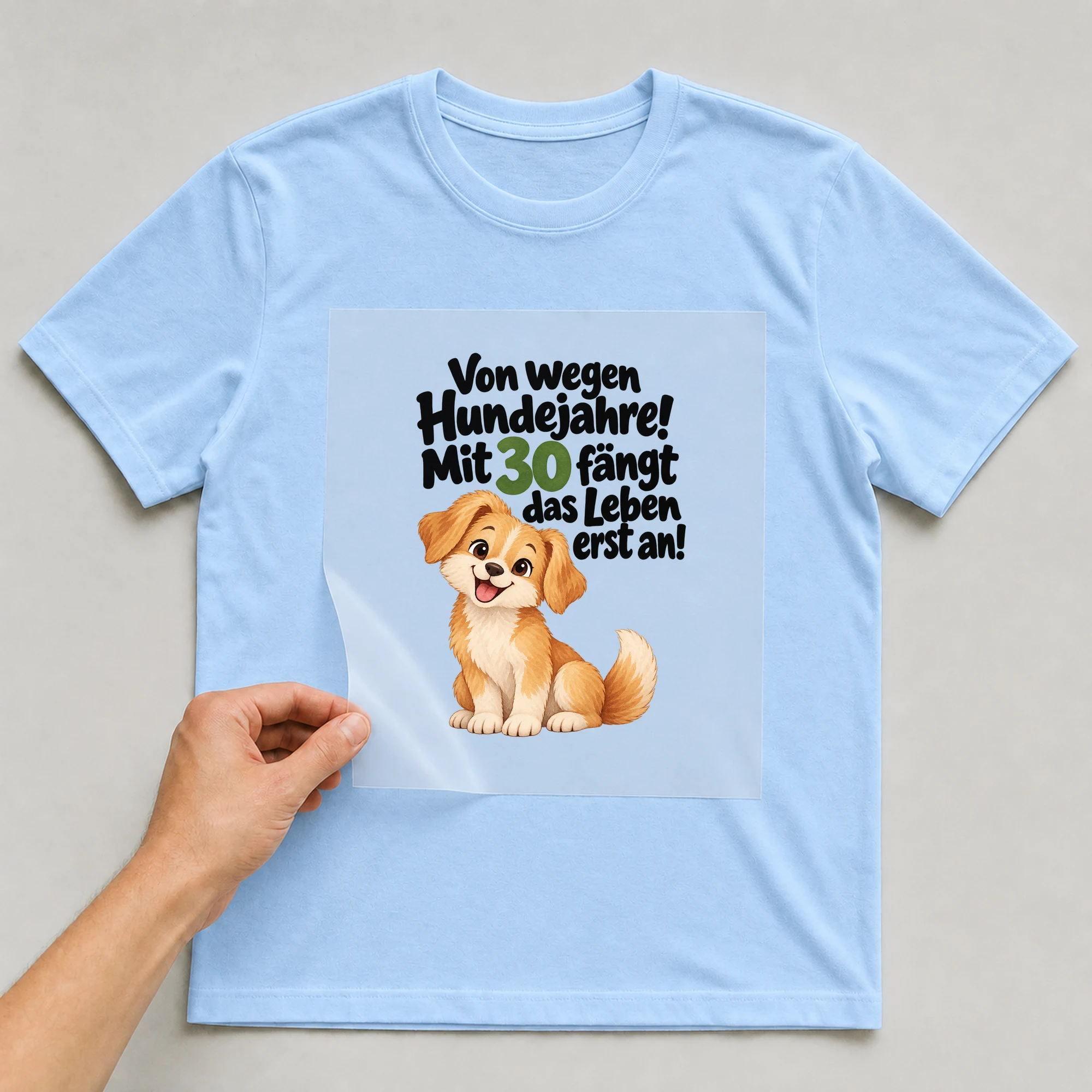 Bügelbild „Von wegen Hundejahre! Mit 30 fängt das Leben erst an!“ auf babyblauem T-Shirt, Folie wird aufgelegt