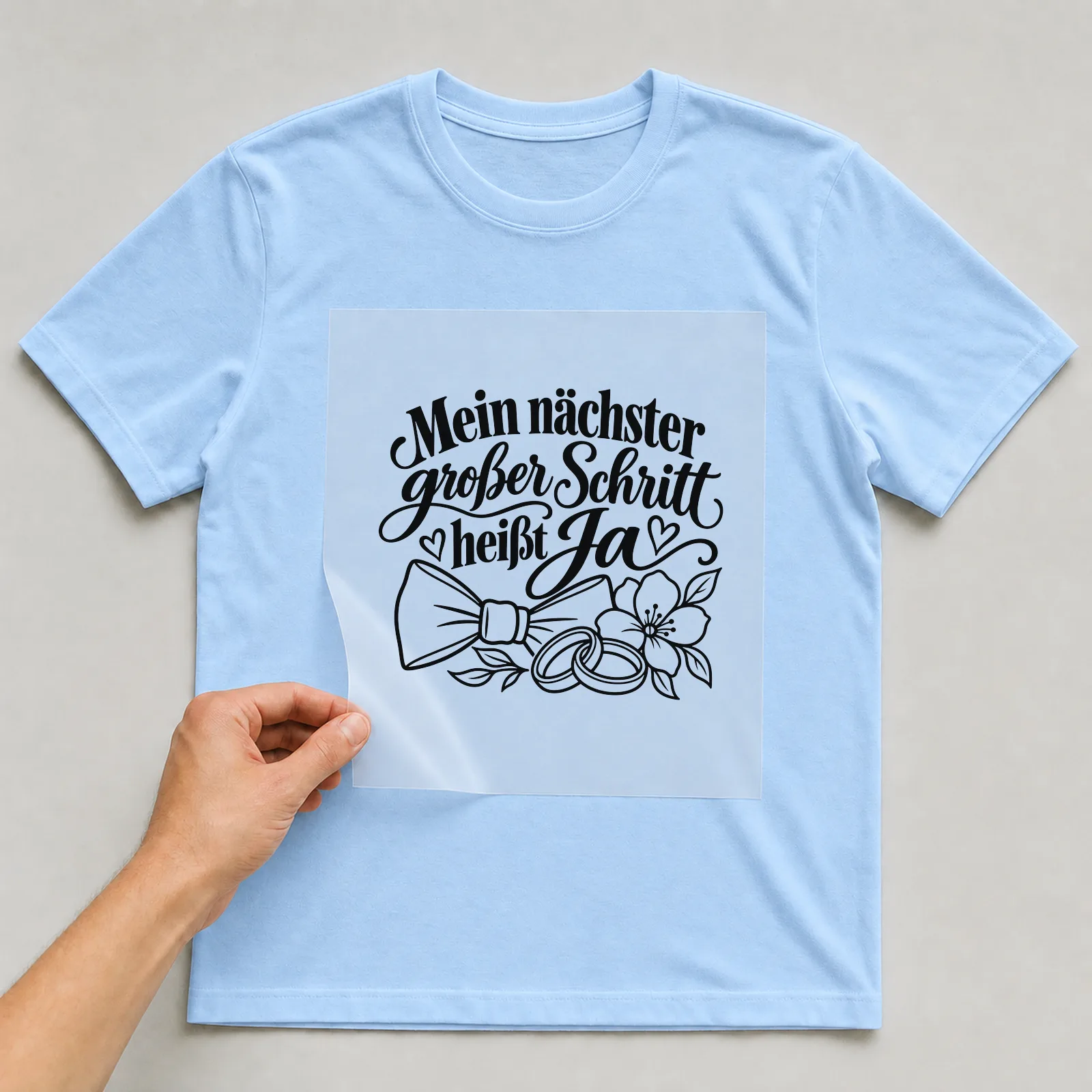 Bügelbild „Mein nächster großer Schritt heißt Ja“ auf hellblauem T-Shirt, Folie wird aufgelegt