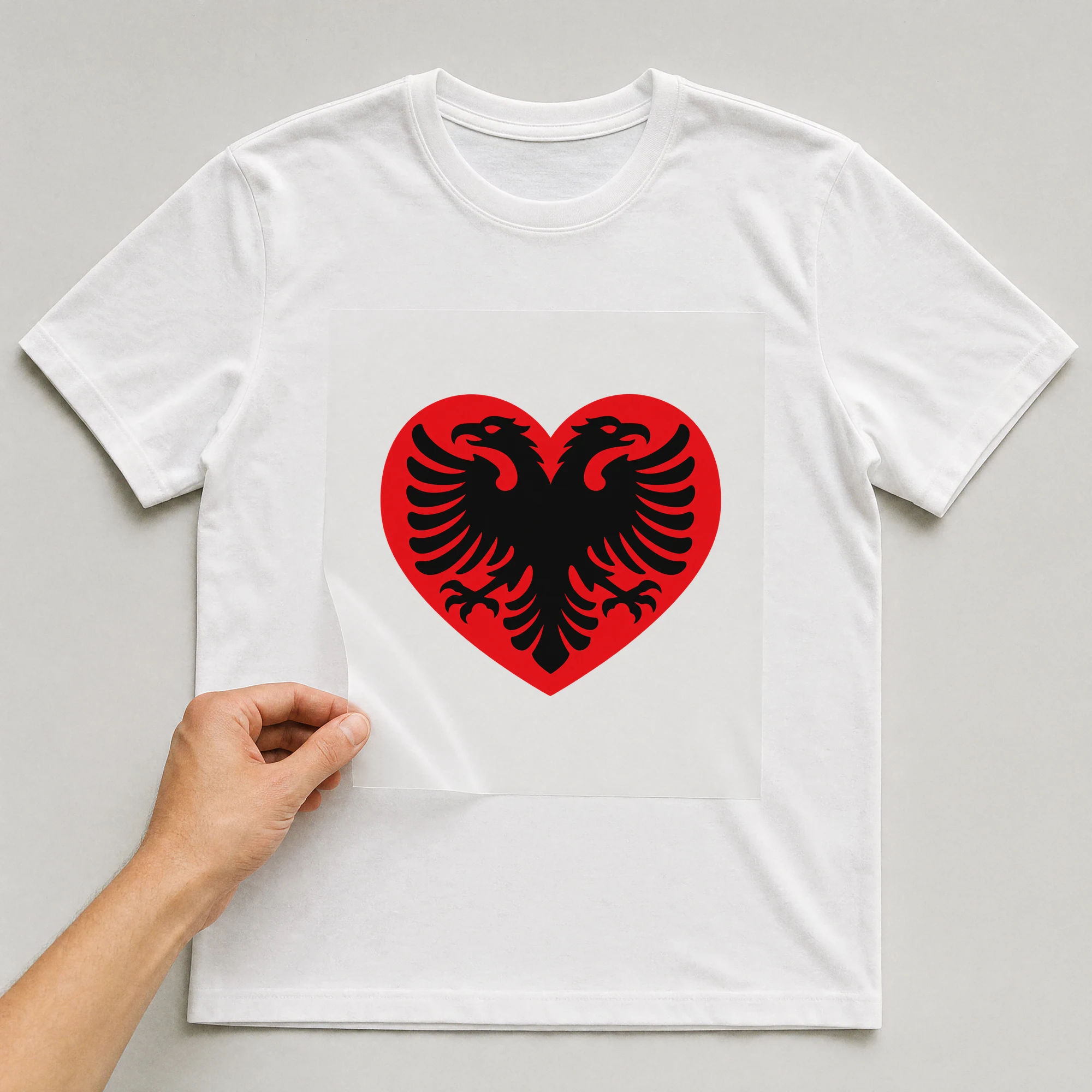Bügelbild „Länder Flagge Albanien“ auf weißem T-Shirt, Folie wird aufgelegt