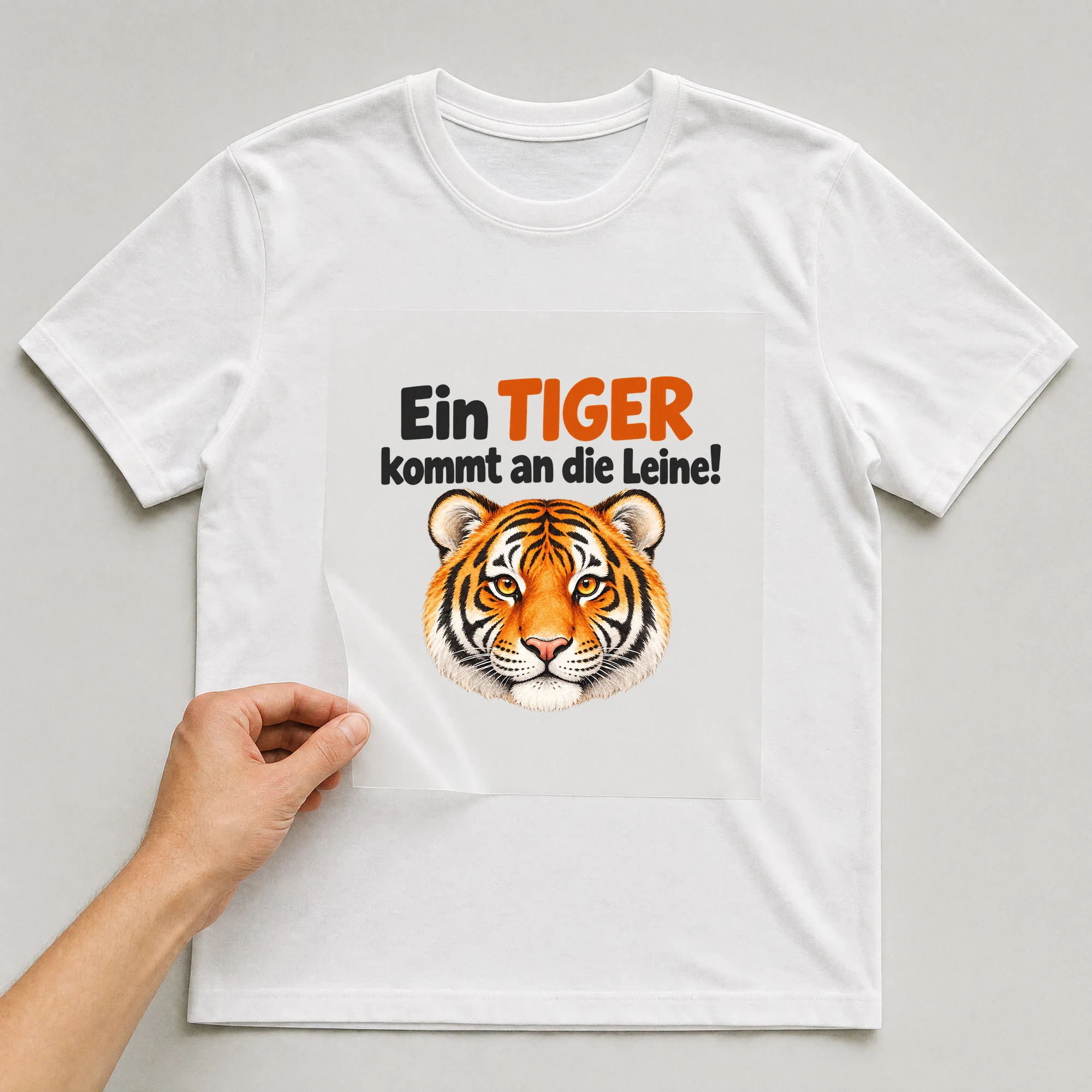 Bügelbild „Ein TIGER kommt an die Leine!“ auf weißem T-Shirt, Folie wird aufgelegt