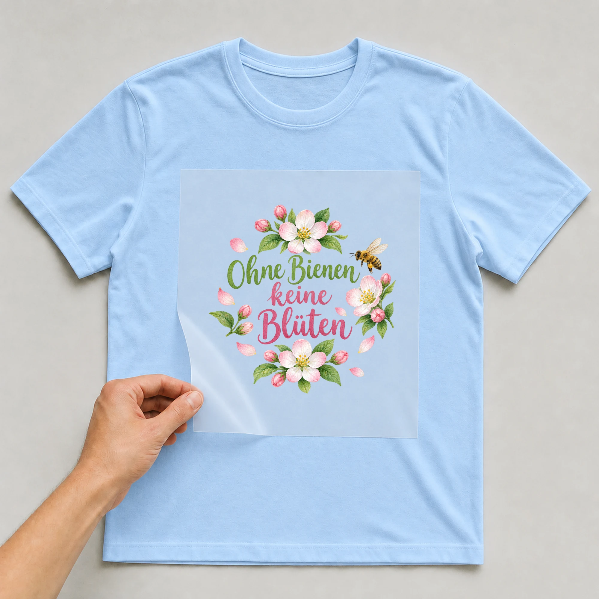 Bügelbild „Ohne Bienen keine Blüten“ auf babyblauem T-Shirt, Folie wird aufgelegt