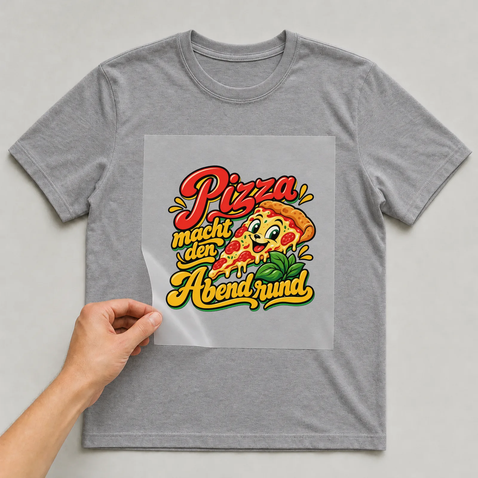 Bügelbild „Pizza macht den Abend rund“ auf grauem T-Shirt, Folie wird aufgelegt