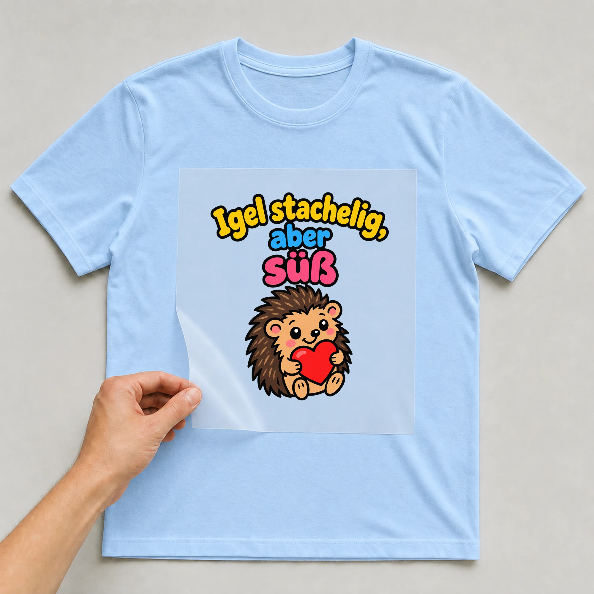 Bügelbild „Igel stachelig, aber süß“ auf babyblauem T-Shirt, Folie wird aufgelegt