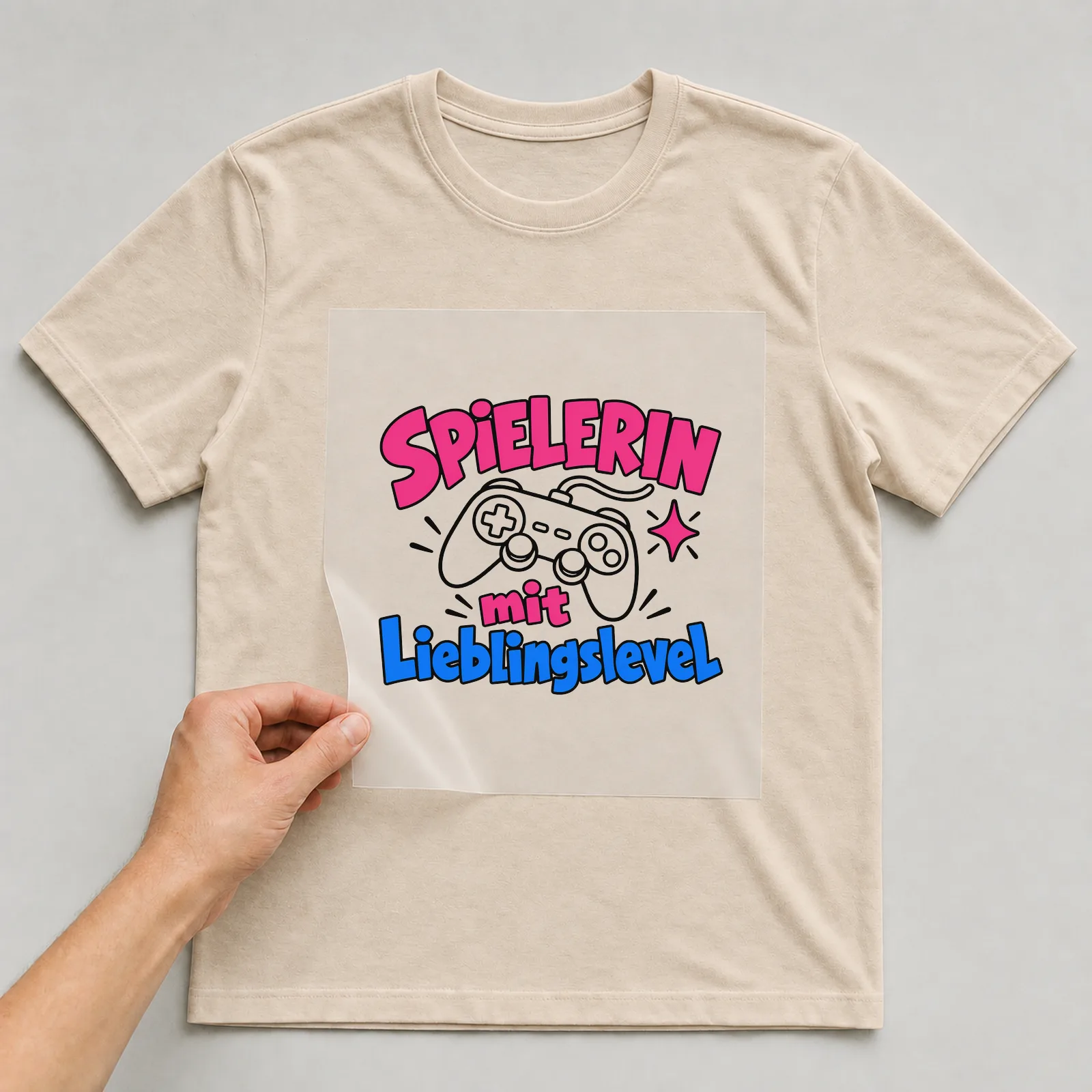 Bügelbild „Spielerin mit Lieblingslevel“ auf beigem T-Shirt, Folie wird aufgelegt