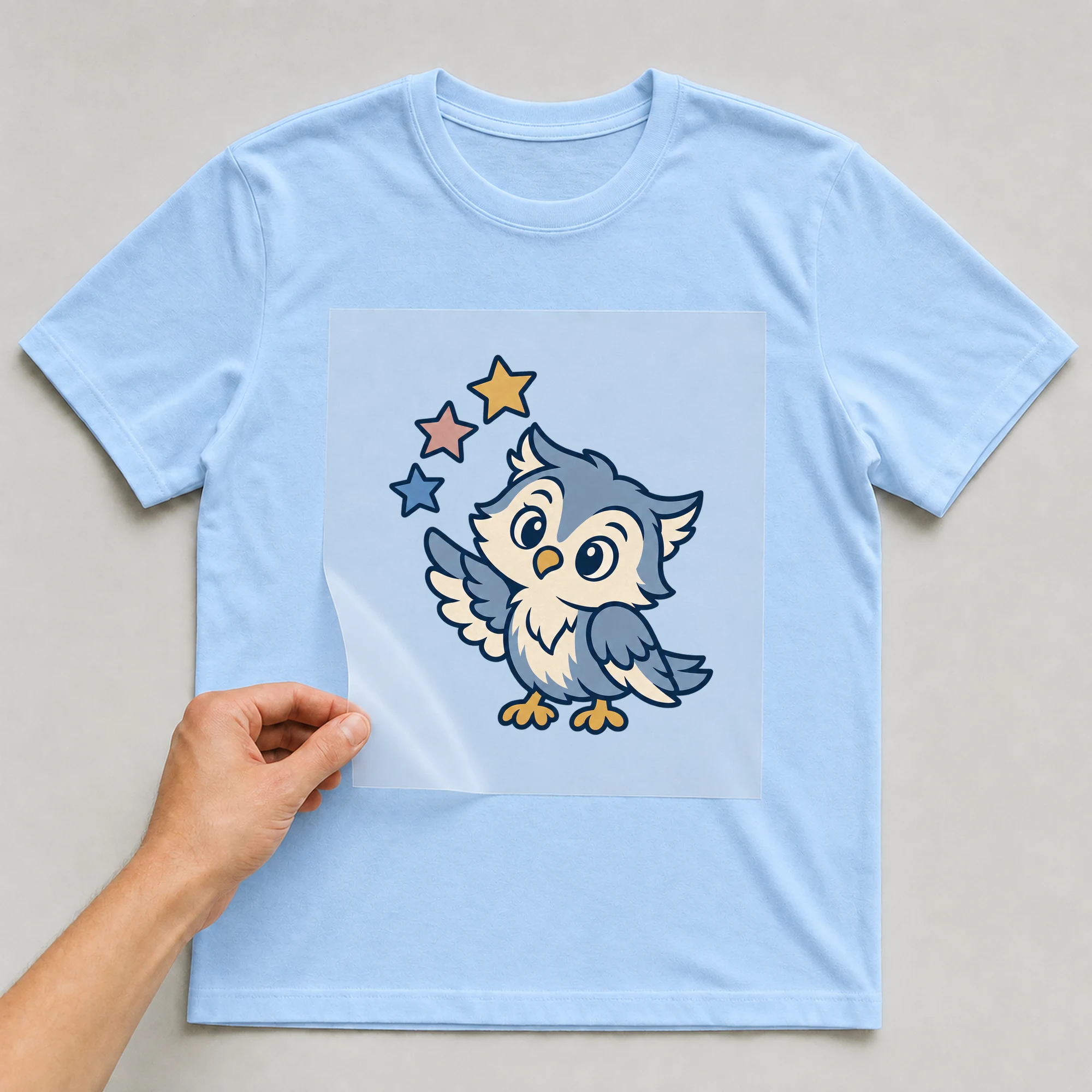 Bügelbild „BB021161-motiv-r03705“ auf babyblauem T-Shirt, Folie wird aufgelegt