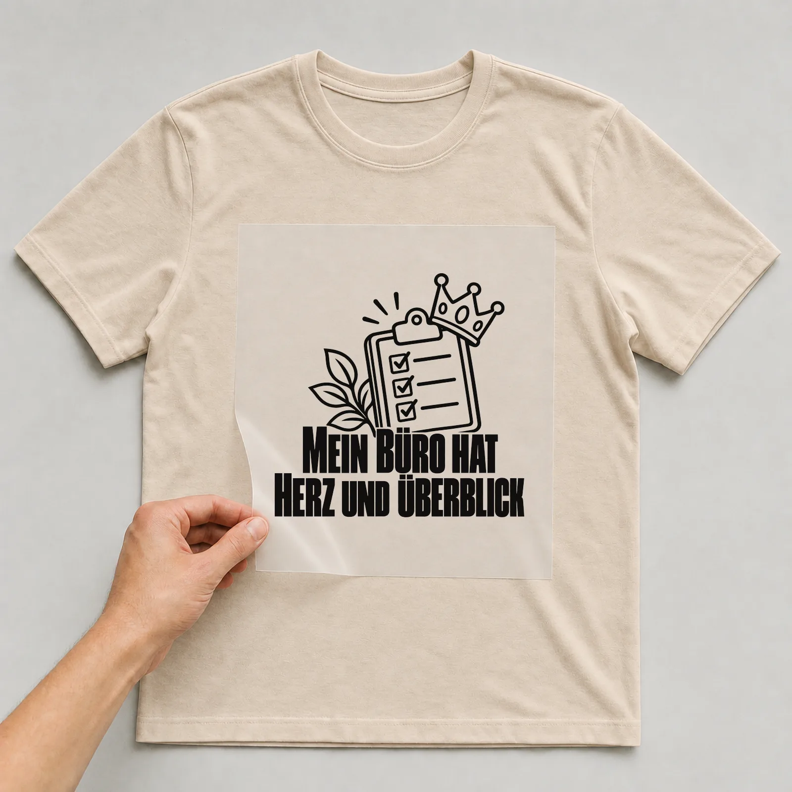 Bügelbild „Mein Büro hat Herz und Überblick“ auf beigem T-Shirt, Folie wird aufgelegt