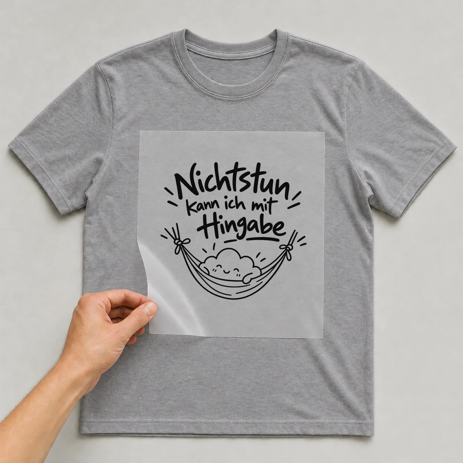 Bügelbild „Nichtstun kann ich mit Hingabe“ auf grauem T-Shirt, Folie wird aufgelegt