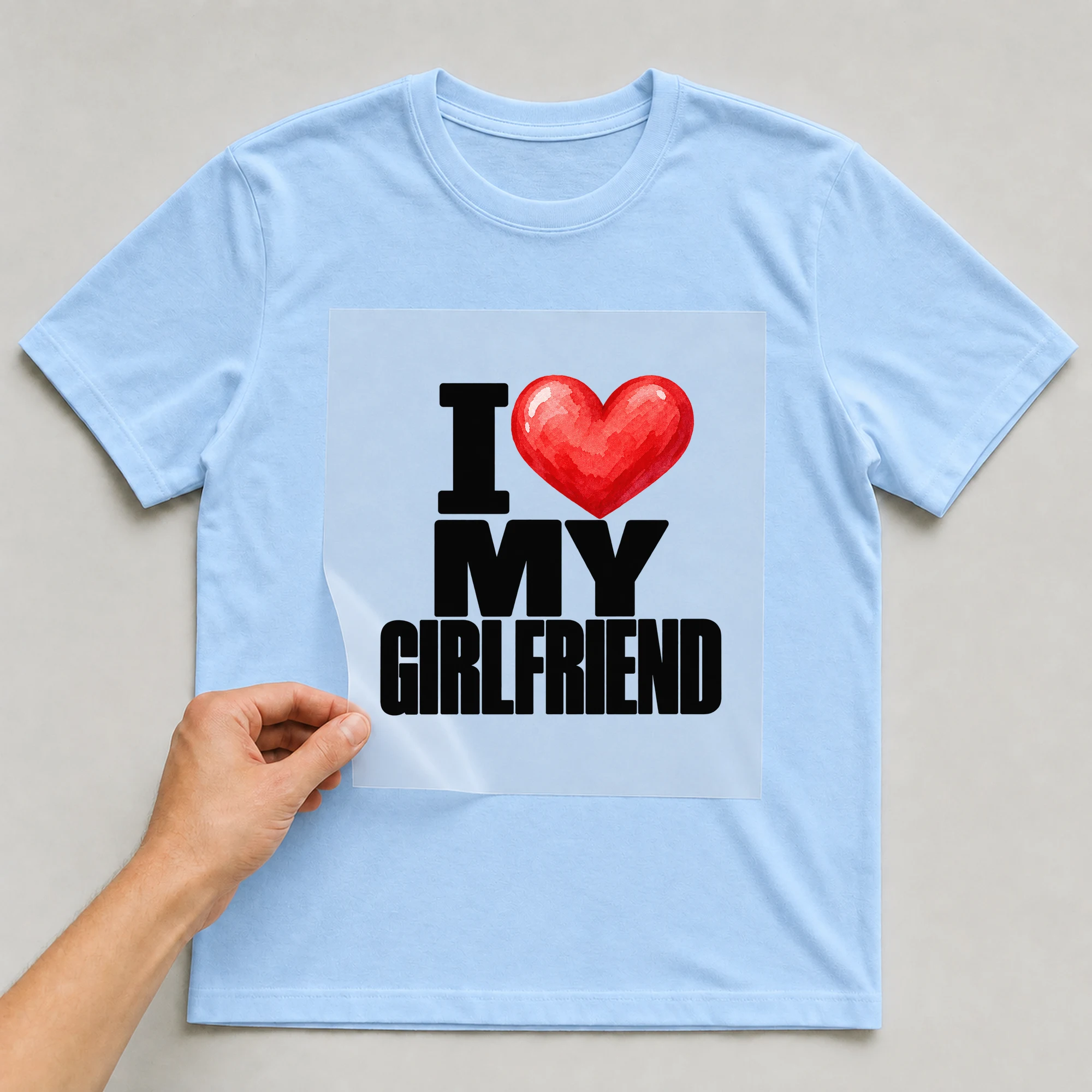 Bügelbild „I My Girlfriend“ auf babyblauem T-Shirt, Folie wird aufgelegt