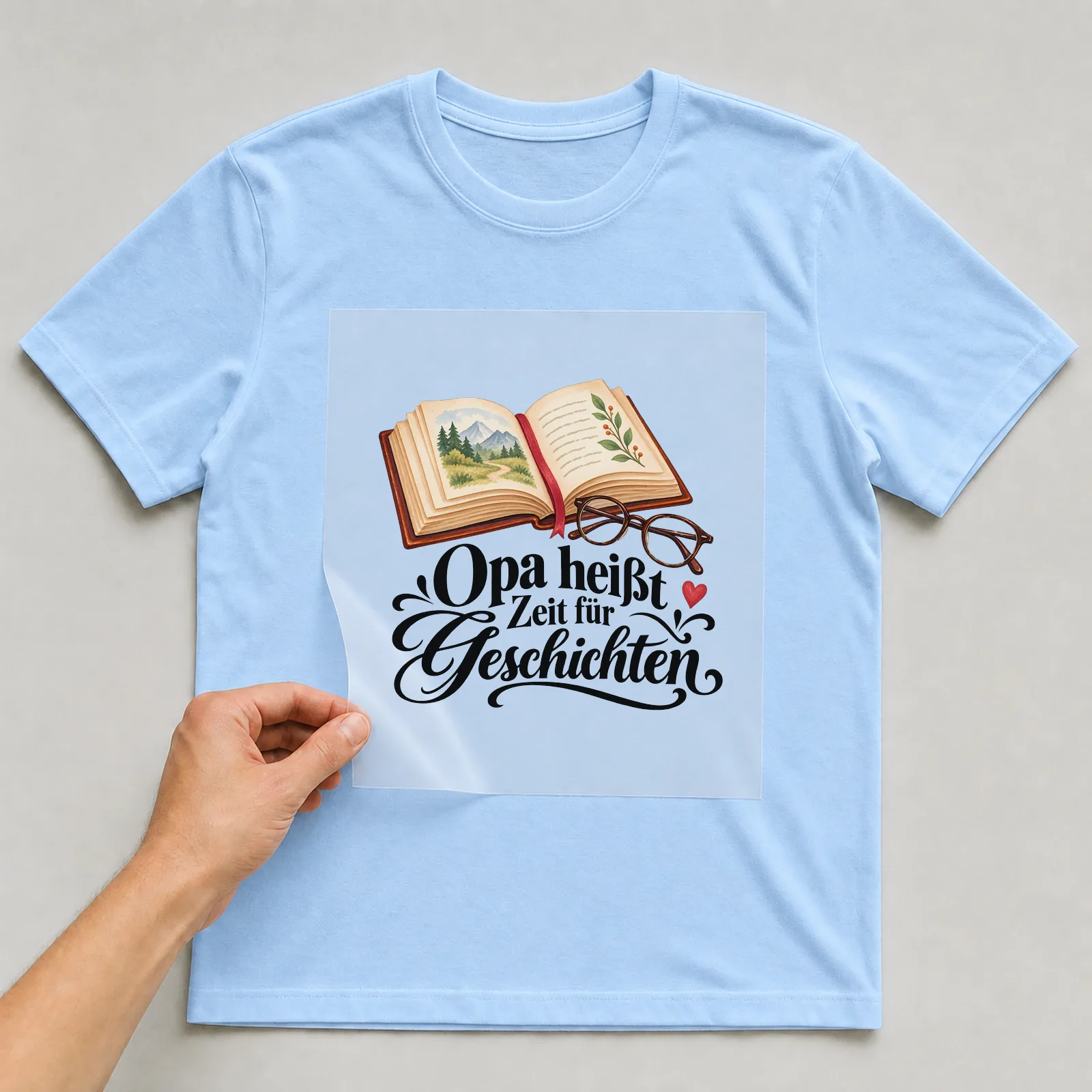 Bügelbild „Opa heißt Zeit für Geschichten“ auf hellblauem T-Shirt, Folie wird aufgelegt