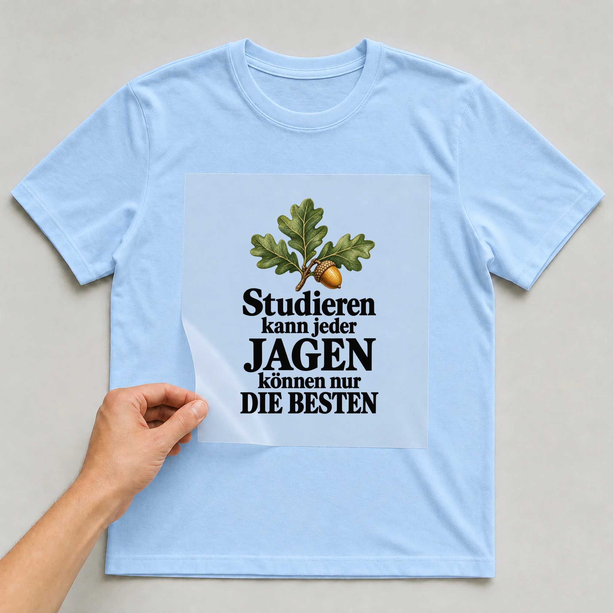 Bügelbild „Studieren Kann Jeder Jagen Können Nur Die Besten“ auf babyblauem T-Shirt, Folie wird aufgelegt