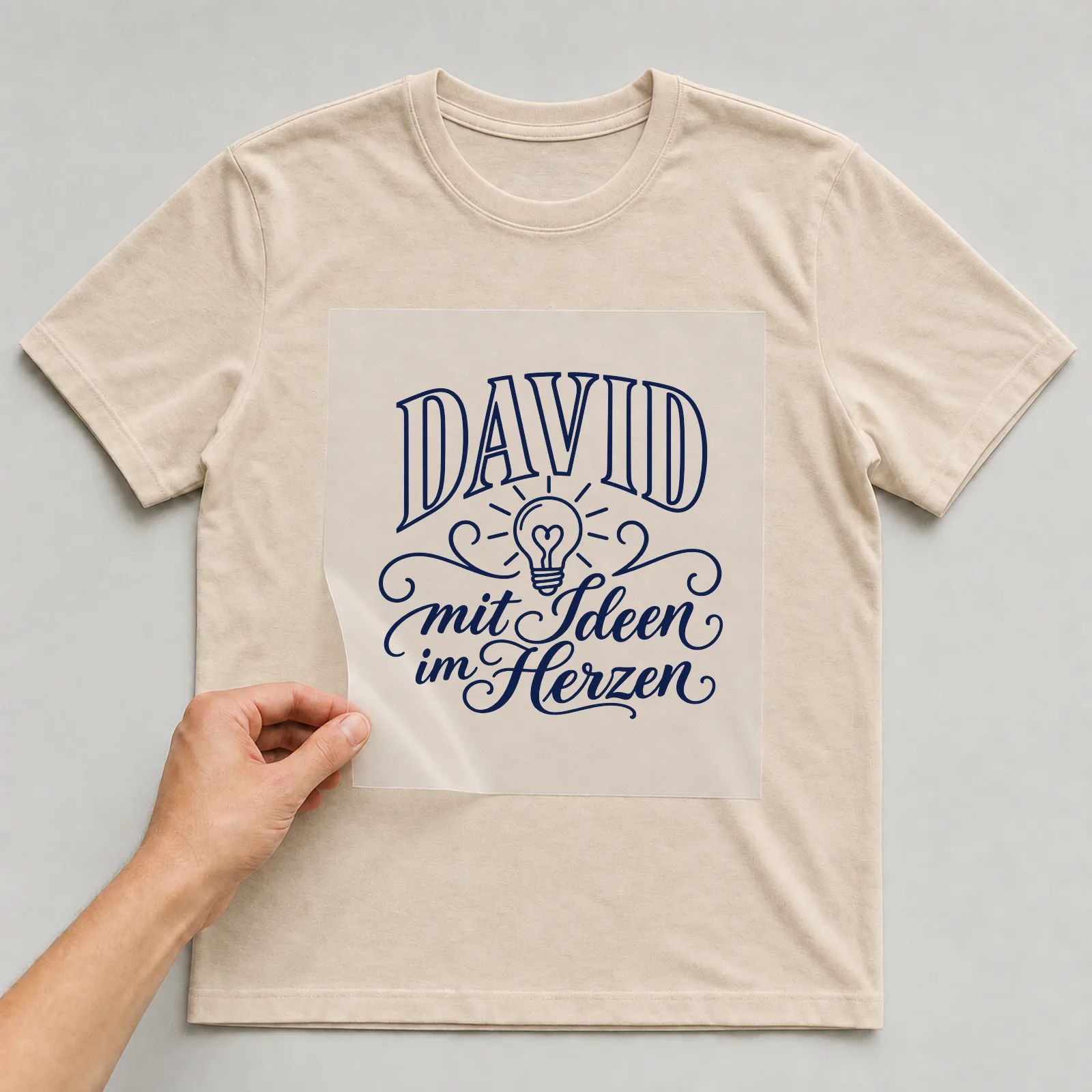 Bügelbild „David mit Ideen im Herzen“ auf beigem T-Shirt, Folie wird aufgelegt