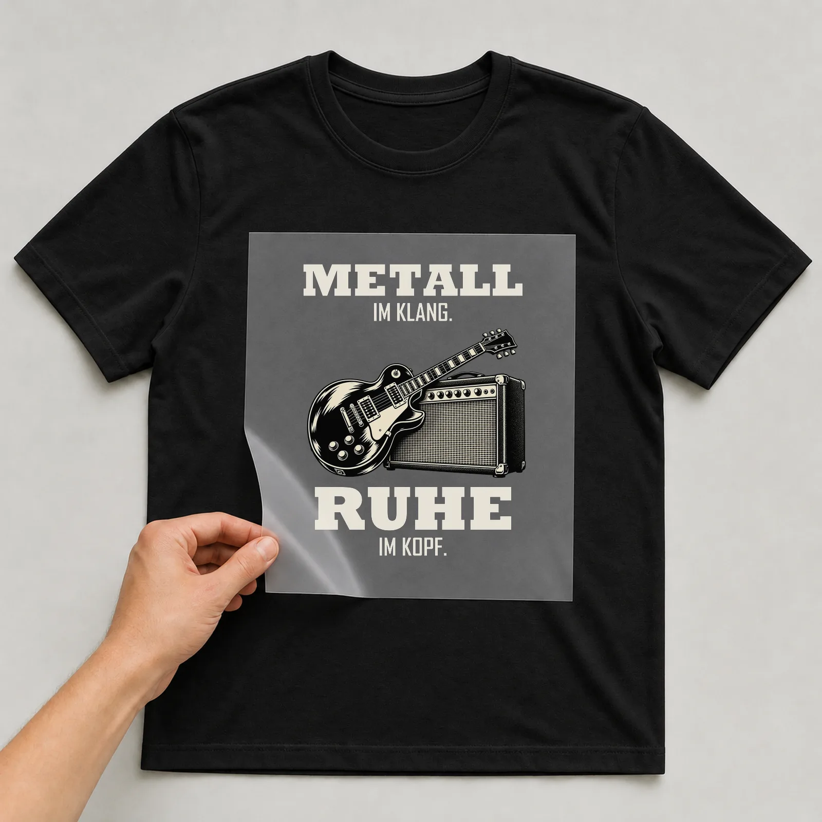 Bügelbild „Metall im klang. Ruhe im Kopf.“ auf schwarzem T-Shirt, Folie wird aufgelegt