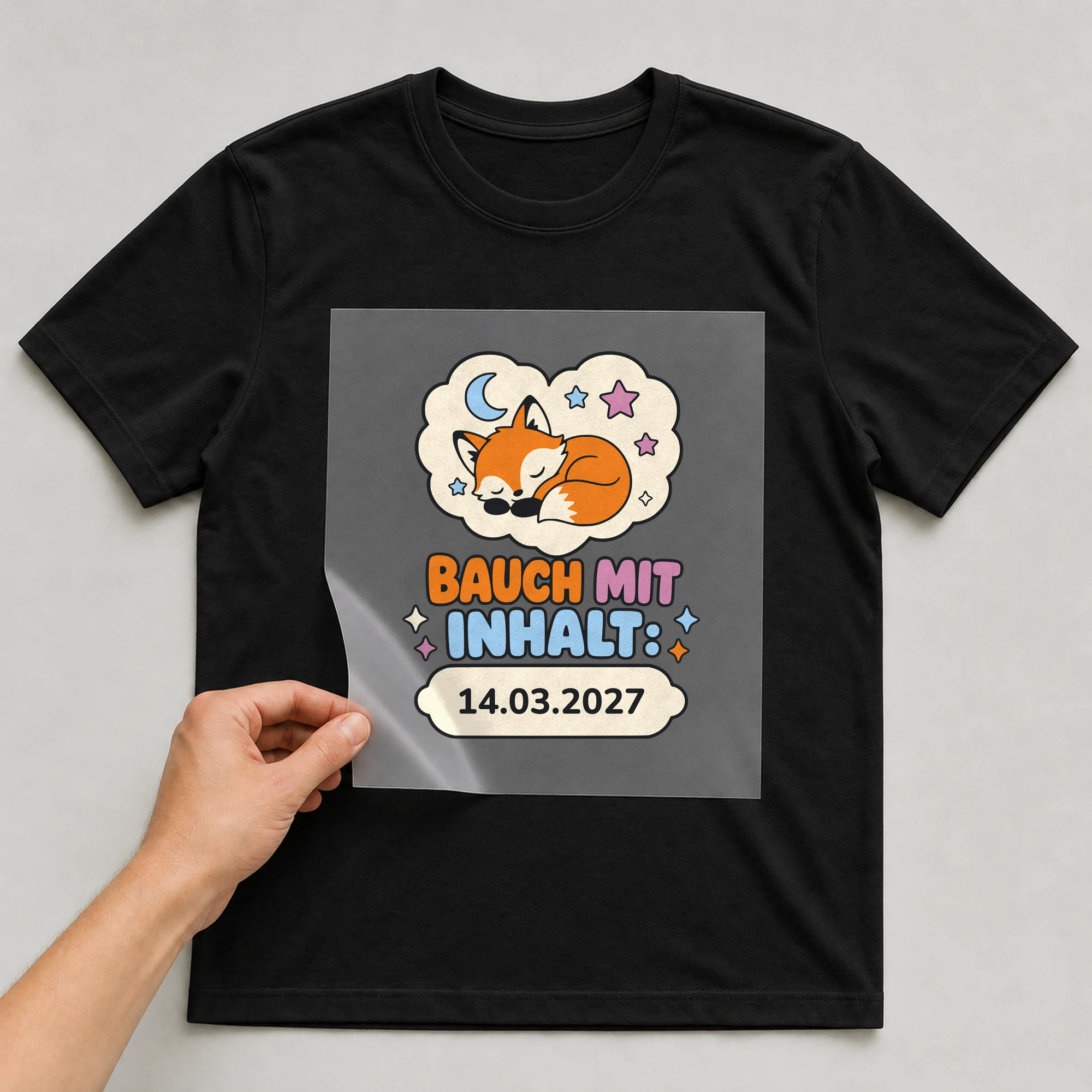 Bügelbild Bauch mit Inhalt mit Datum auf schwarzem T-Shirt, Folie wird aufgelegt