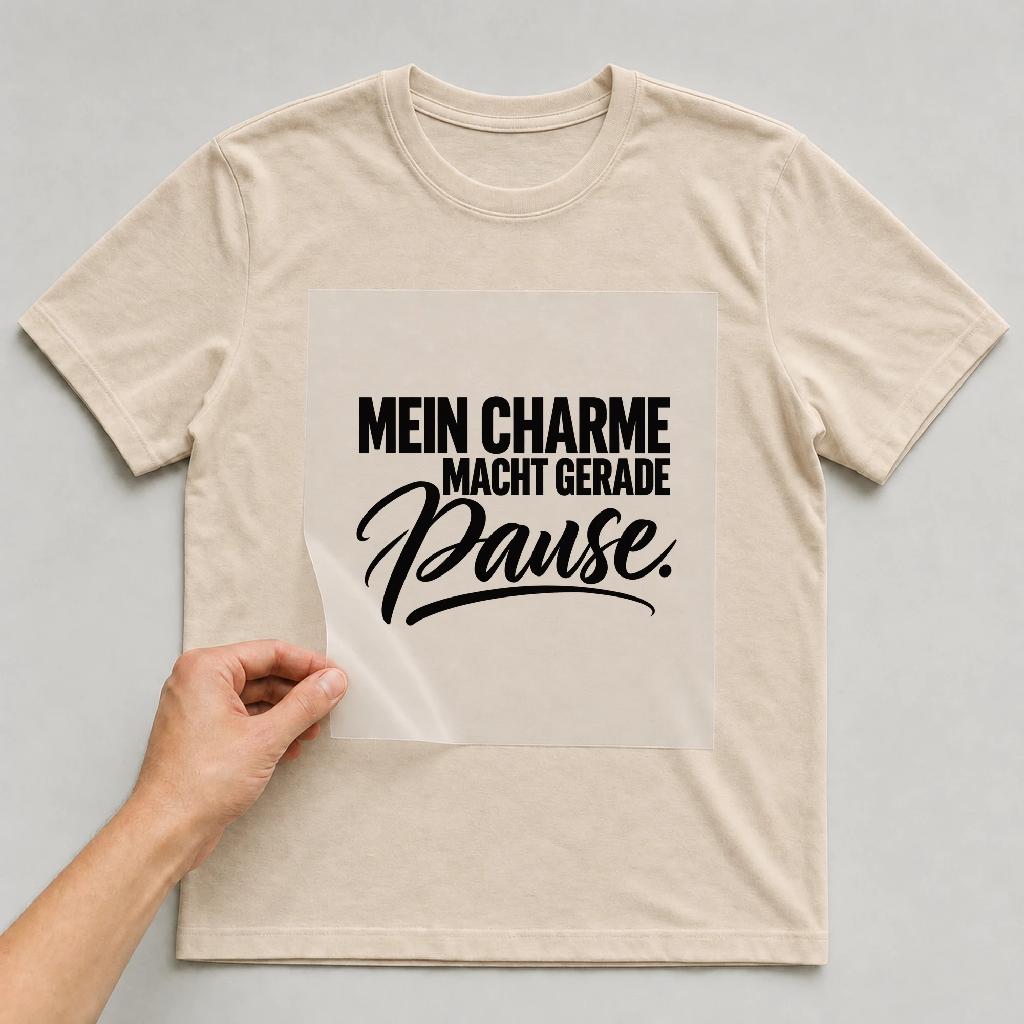 Bügelbild „Mein Charme macht gerade Pause.“ auf babyblauem T-Shirt, Folie wird aufgelegt