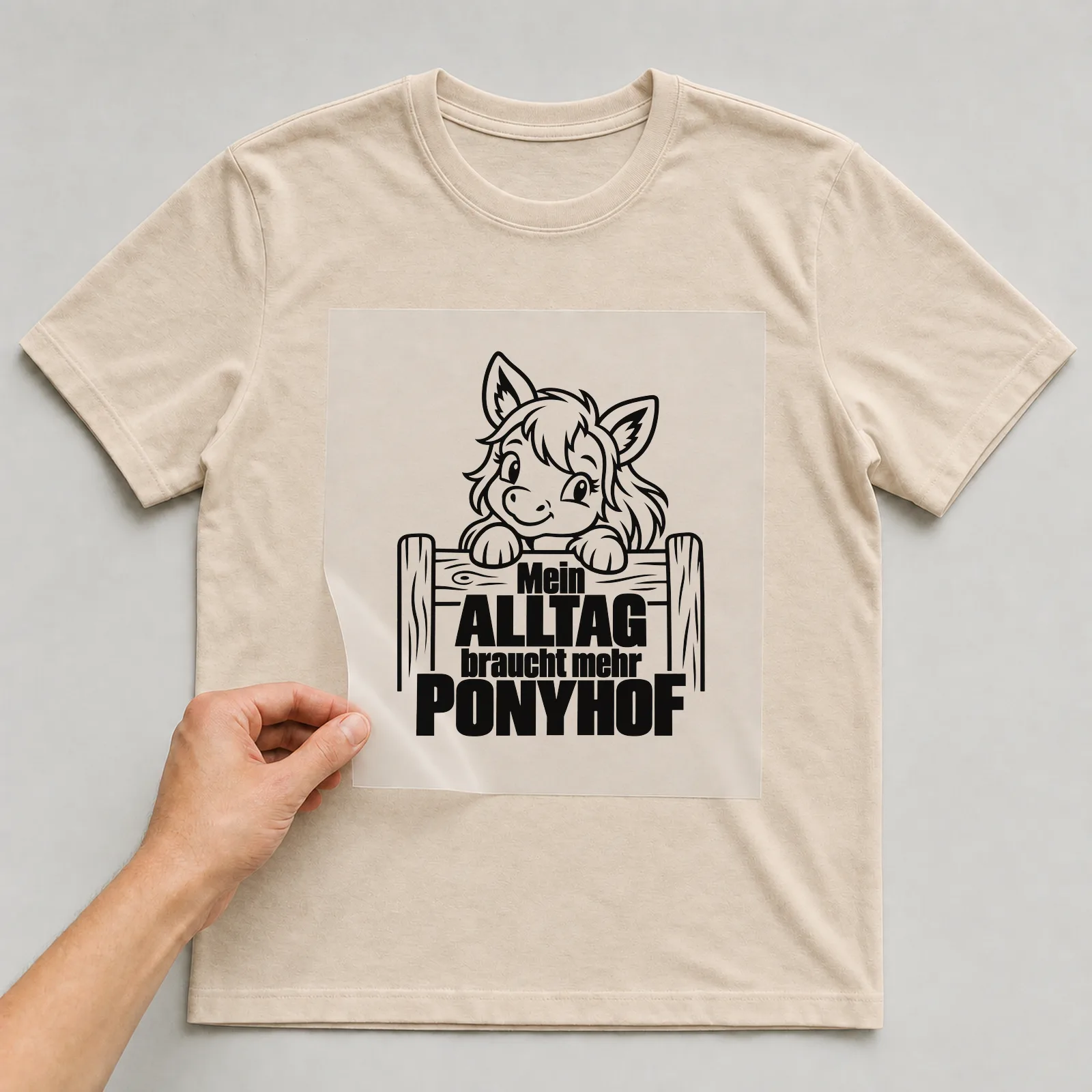 Bügelbild „Mein Alltag braucht mehr Ponyhof“ auf beigem T-Shirt, Folie wird aufgelegt