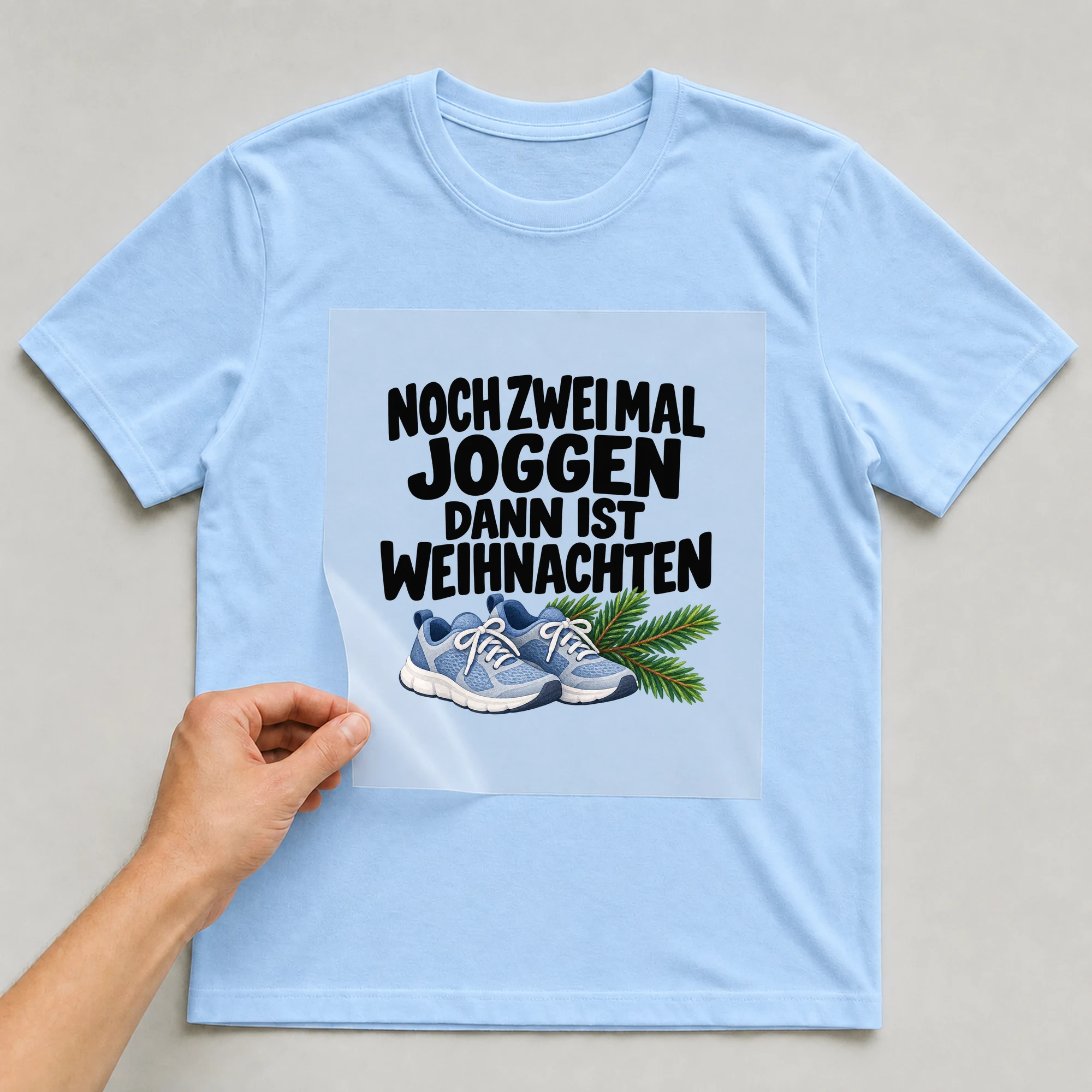 Bügelbild „Noch zwei Mal joggen dann ist Weihnachten“ auf babyblauem T-Shirt, Folie wird aufgelegt