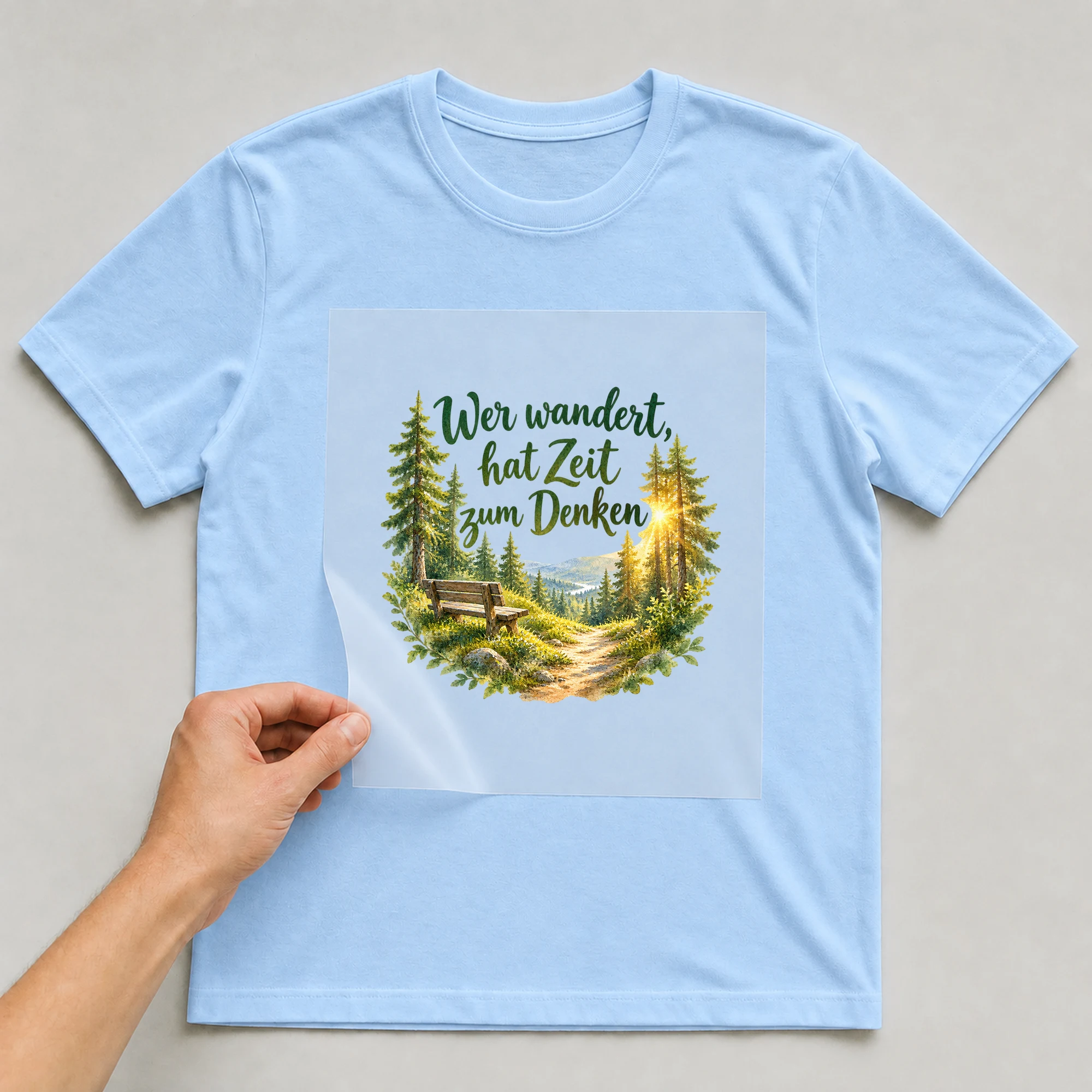Bügelbild „Wer wandert, hat Zeit zum Denken“ auf babyblauem T-Shirt, Folie wird aufgelegt
