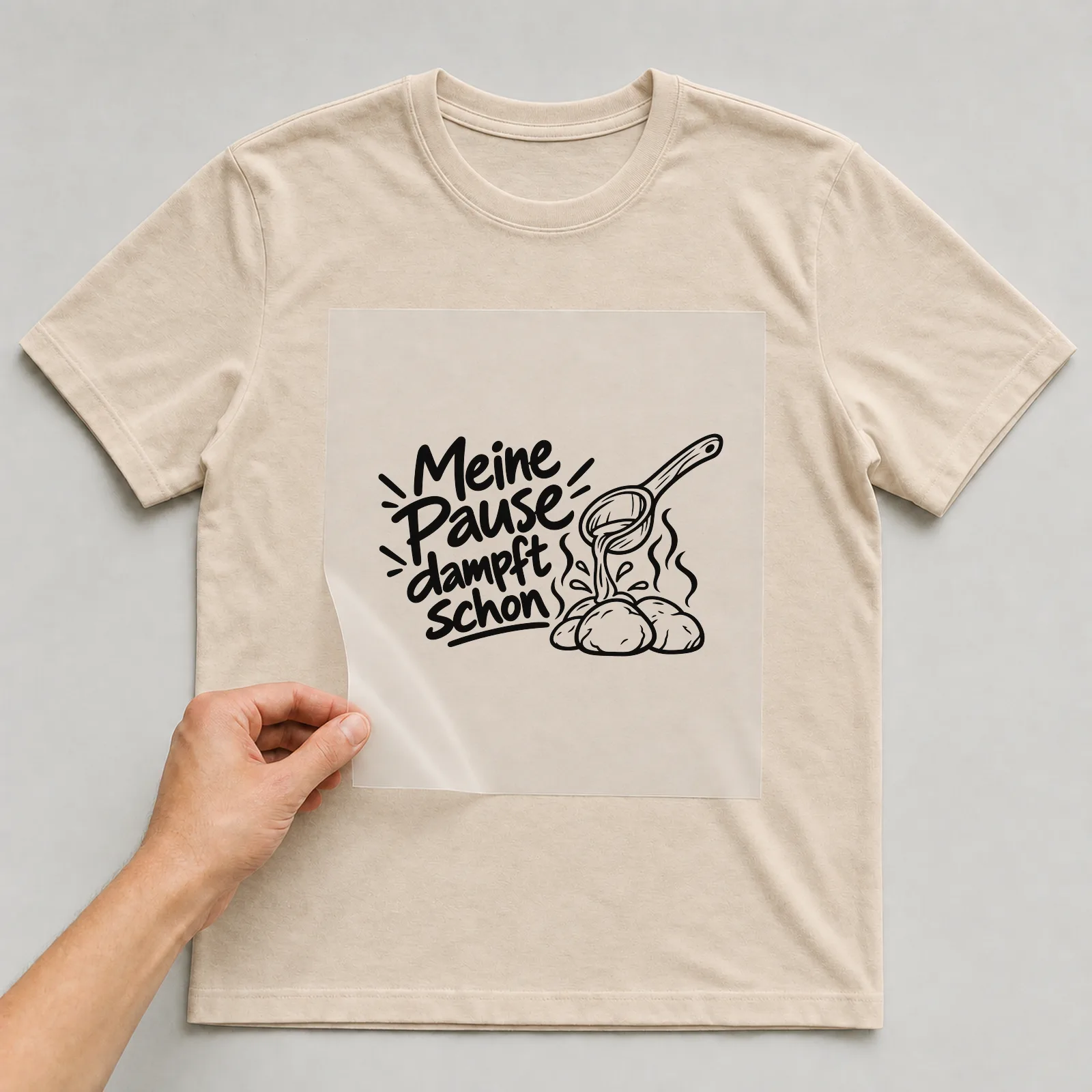 Bügelbild „Meine Pause dampft schon“ auf beigem T-Shirt, Folie wird aufgelegt