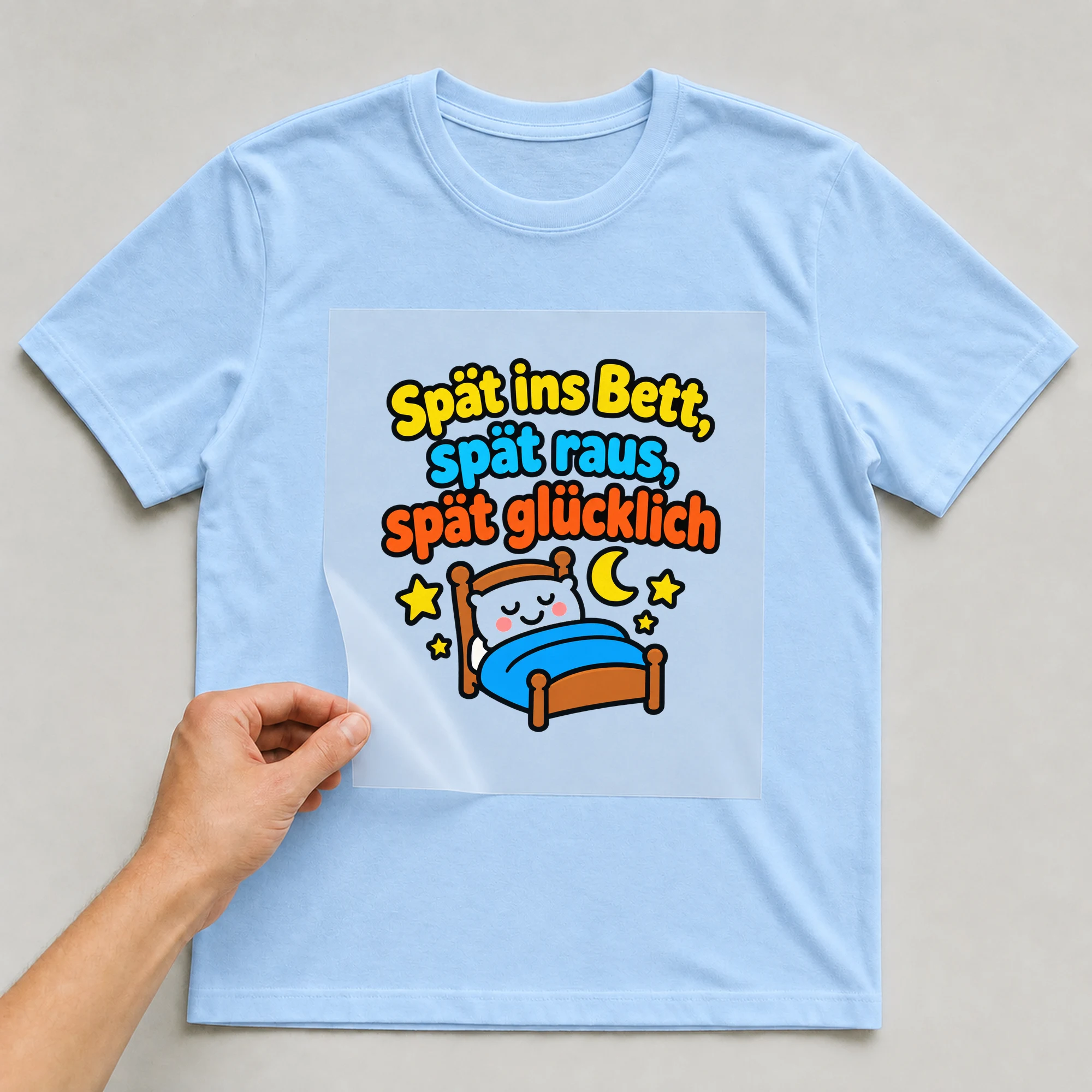 Bügelbild „Spät ins Bett, spät raus, spät glücklich“ auf babyblauem T-Shirt, Folie wird aufgelegt