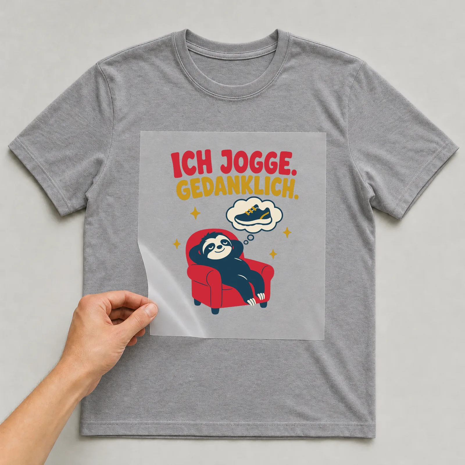 Bügelbild Ich jogge. Gedanklich. auf grauem T-Shirt, Folie wird aufgelegt