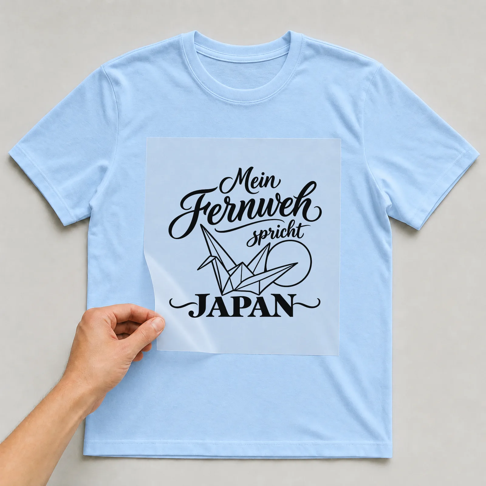 Bügelbild „Mein Fernweh spricht Japan“ auf hellblauem T-Shirt, Folie wird aufgelegt