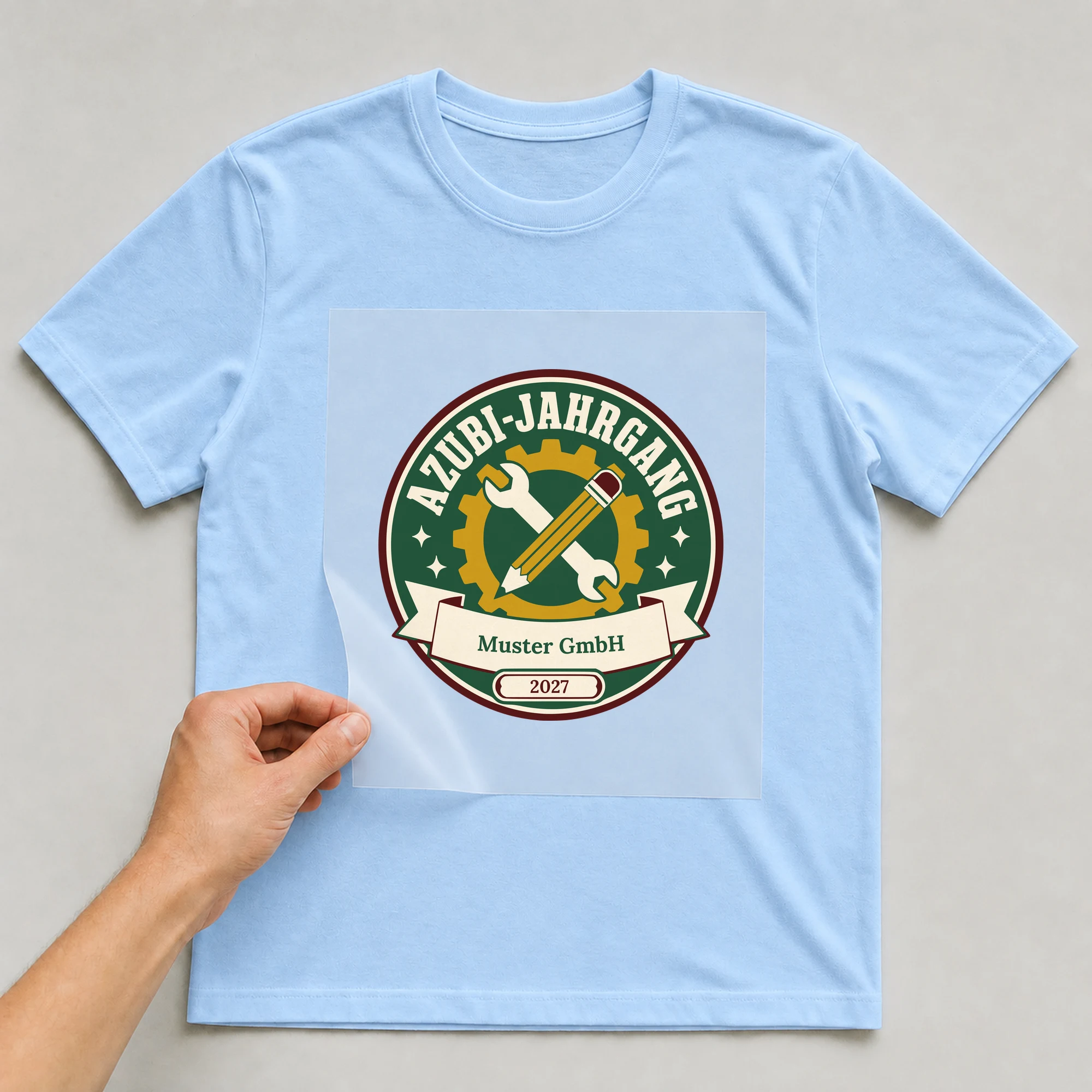 Bügelbild Azubi-Jahrgang mit Firma und Jahr auf hellblauem T-Shirt, Folie wird aufgelegt
